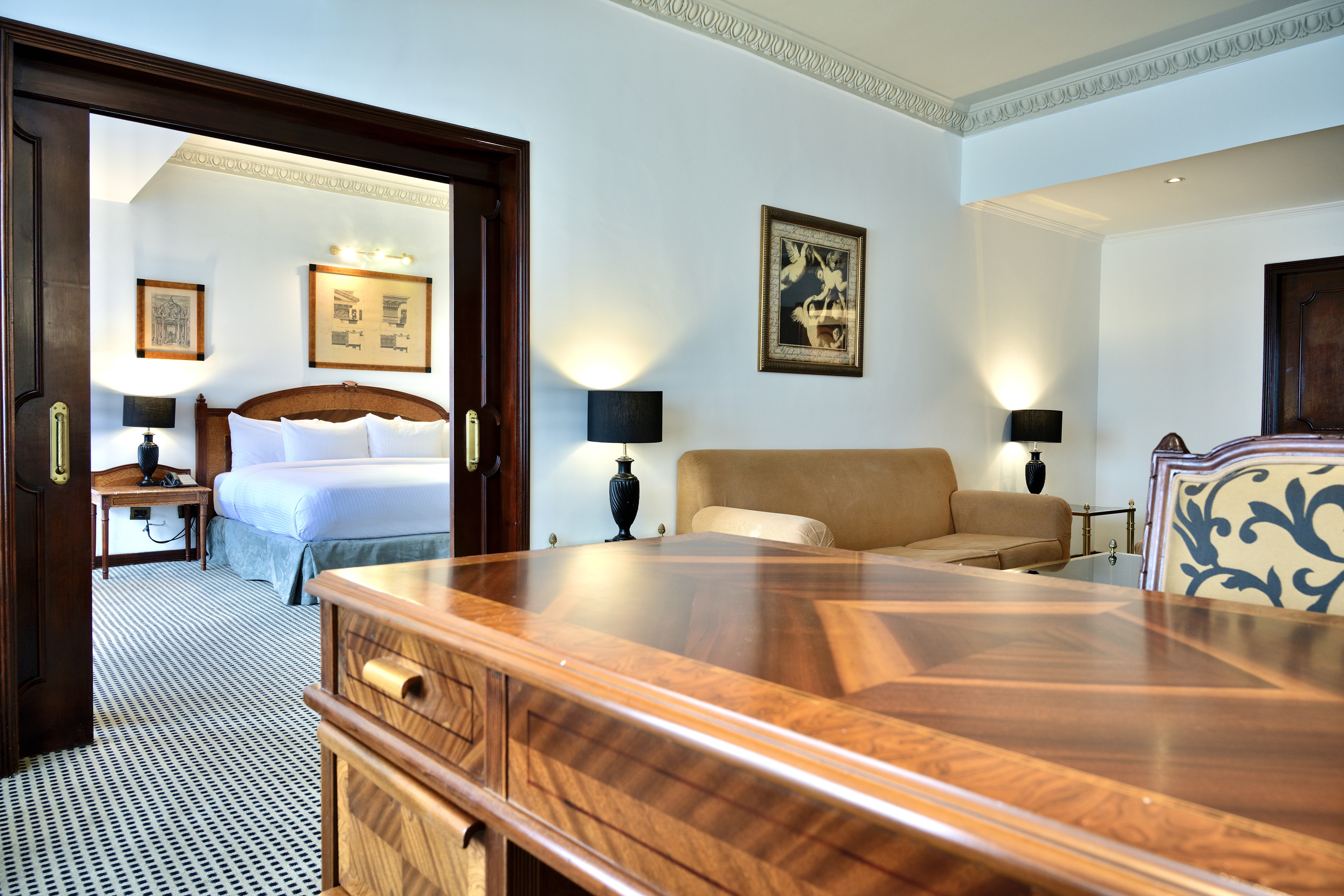Luxury hotel suite: living area, elegant wooden desk, and bedroom.