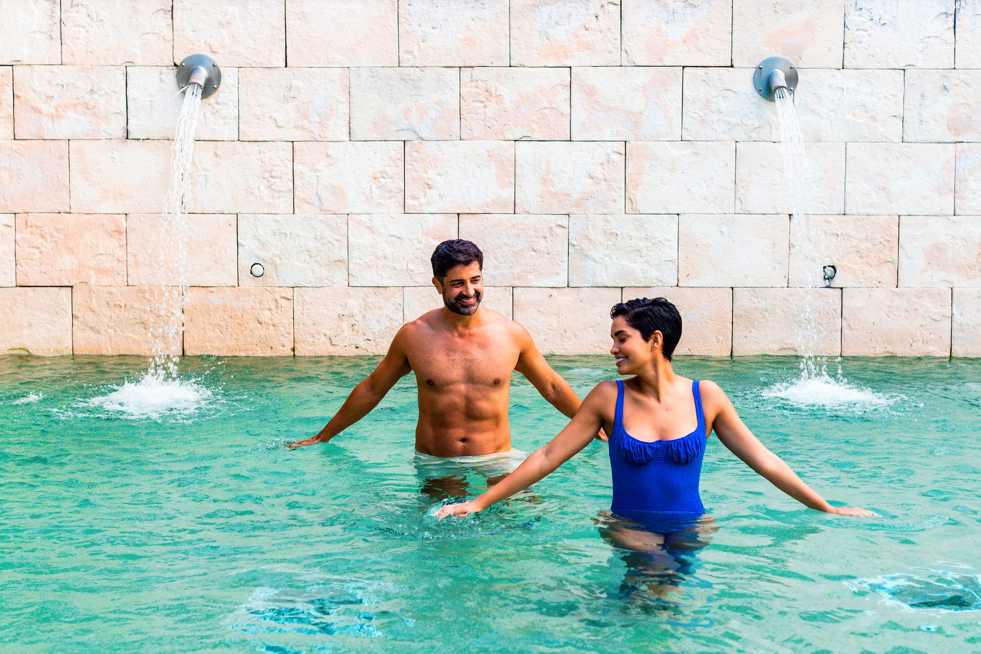 a man and woman in a pool with water jets