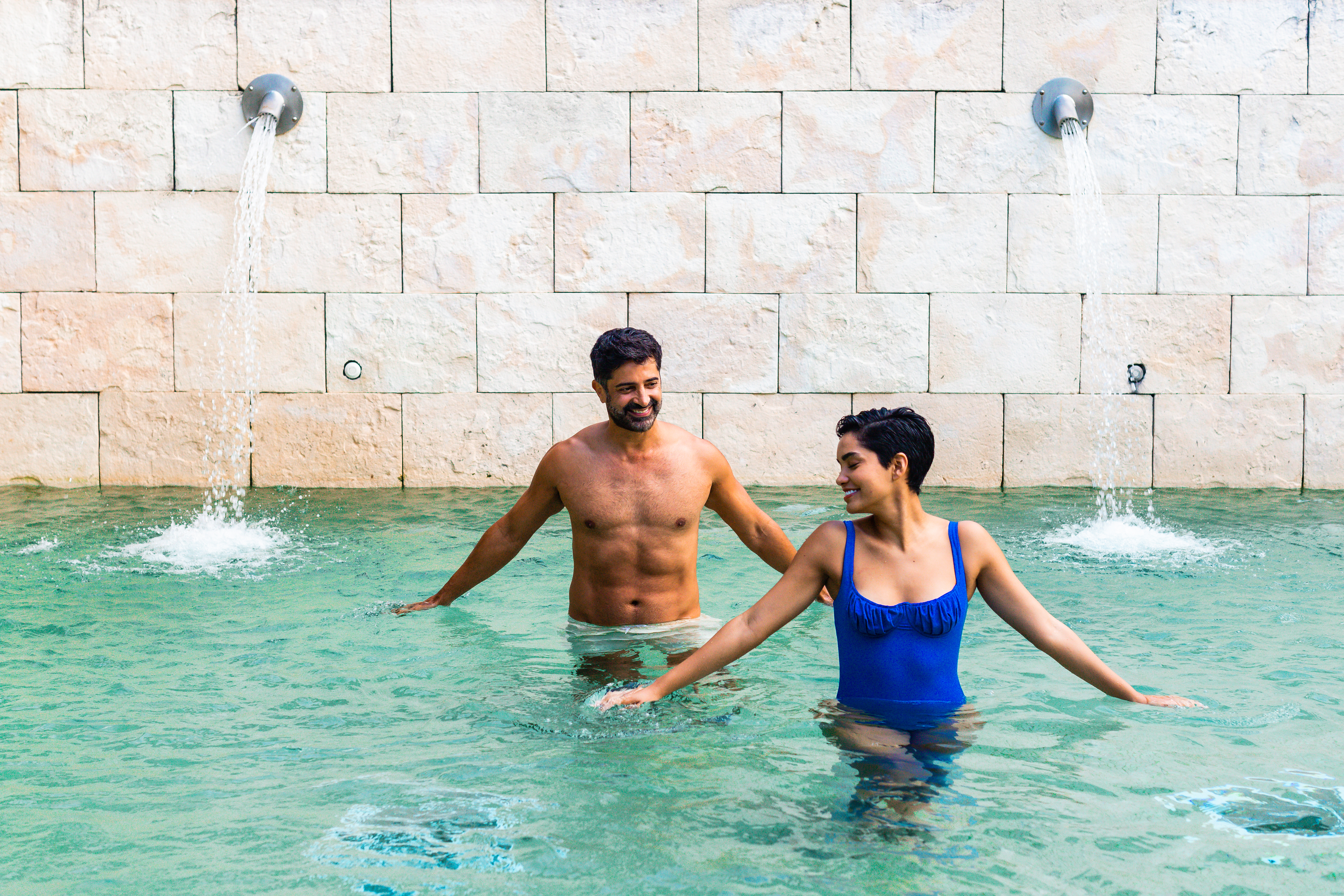 a man and woman in a pool with water jets