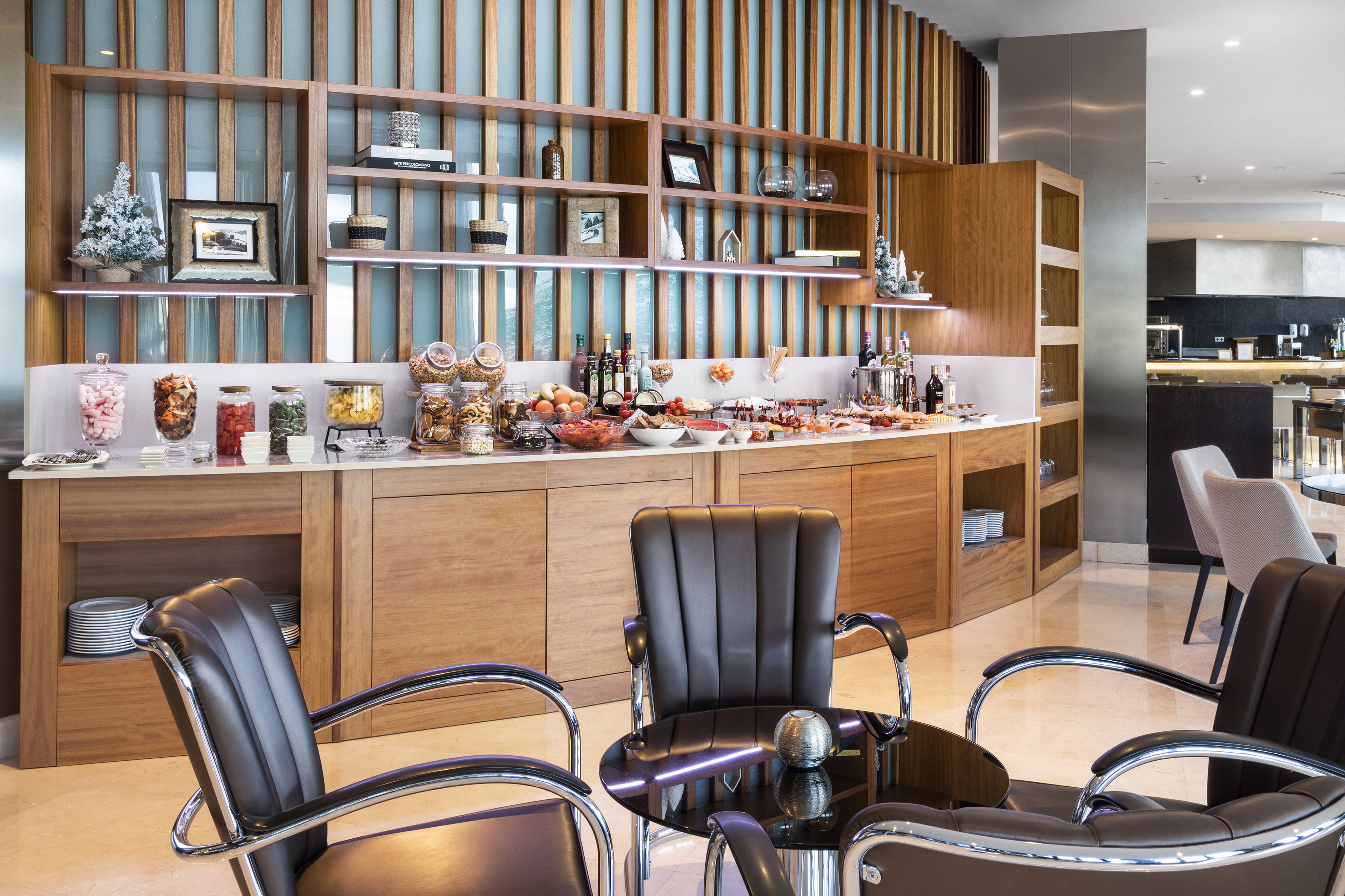 Elegant hotel lounge with a modern buffet of snacks, fruits, and drinks.
