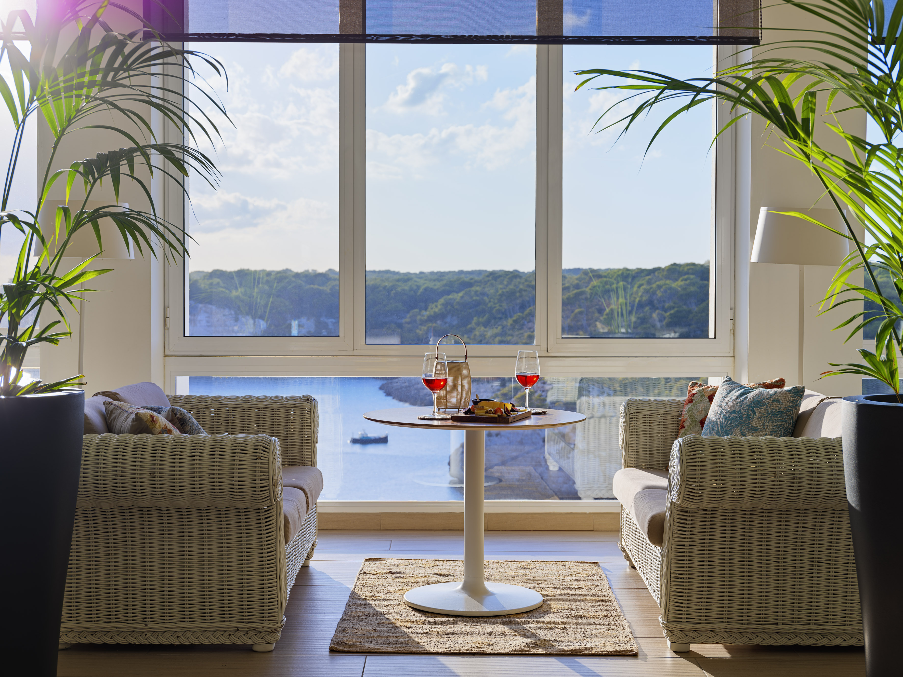 Wicker lounge with wine and snacks, overlooking a stunning ocean bay view.