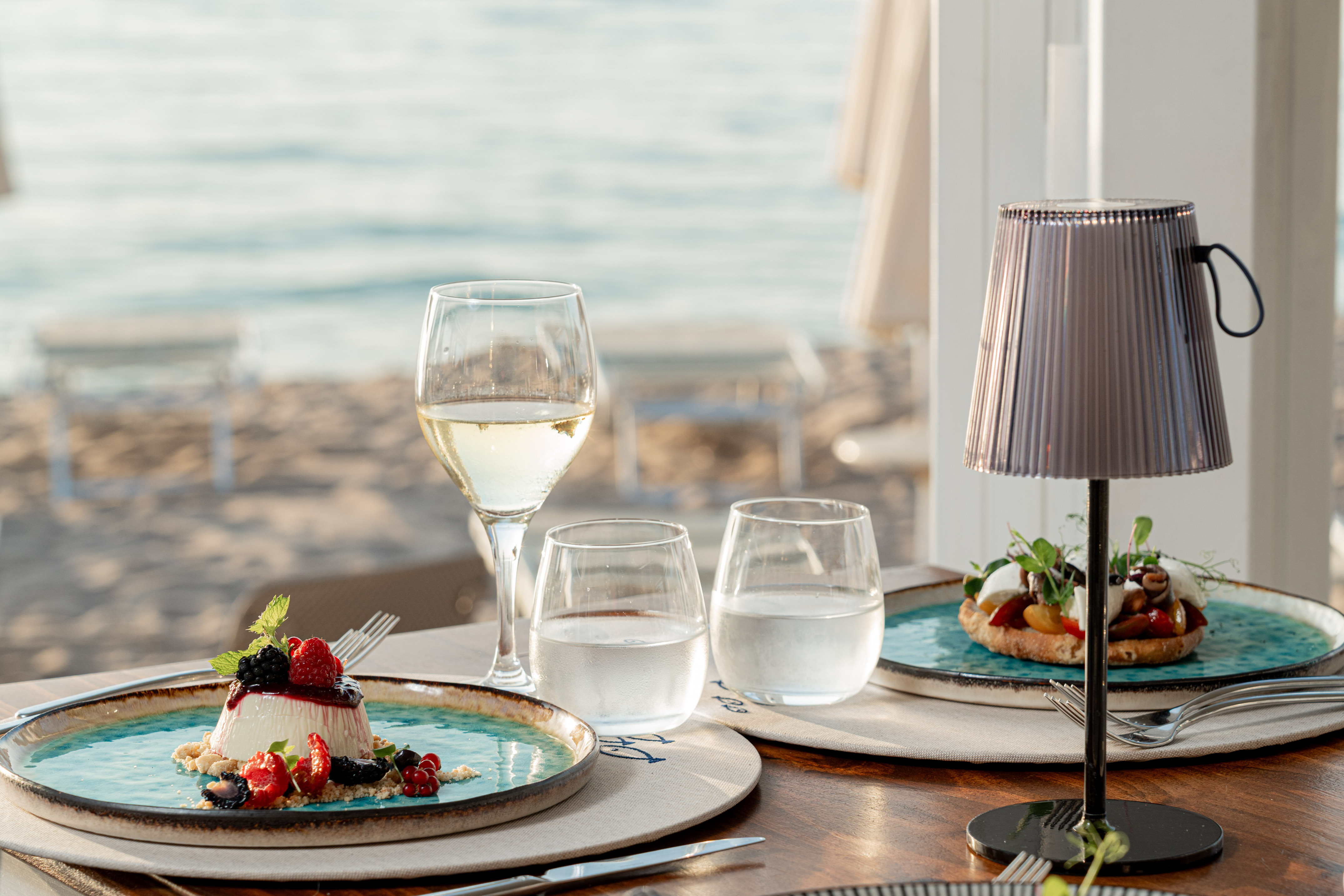 Panna cotta with berries, wine, and savory dish at a beachside restaurant.