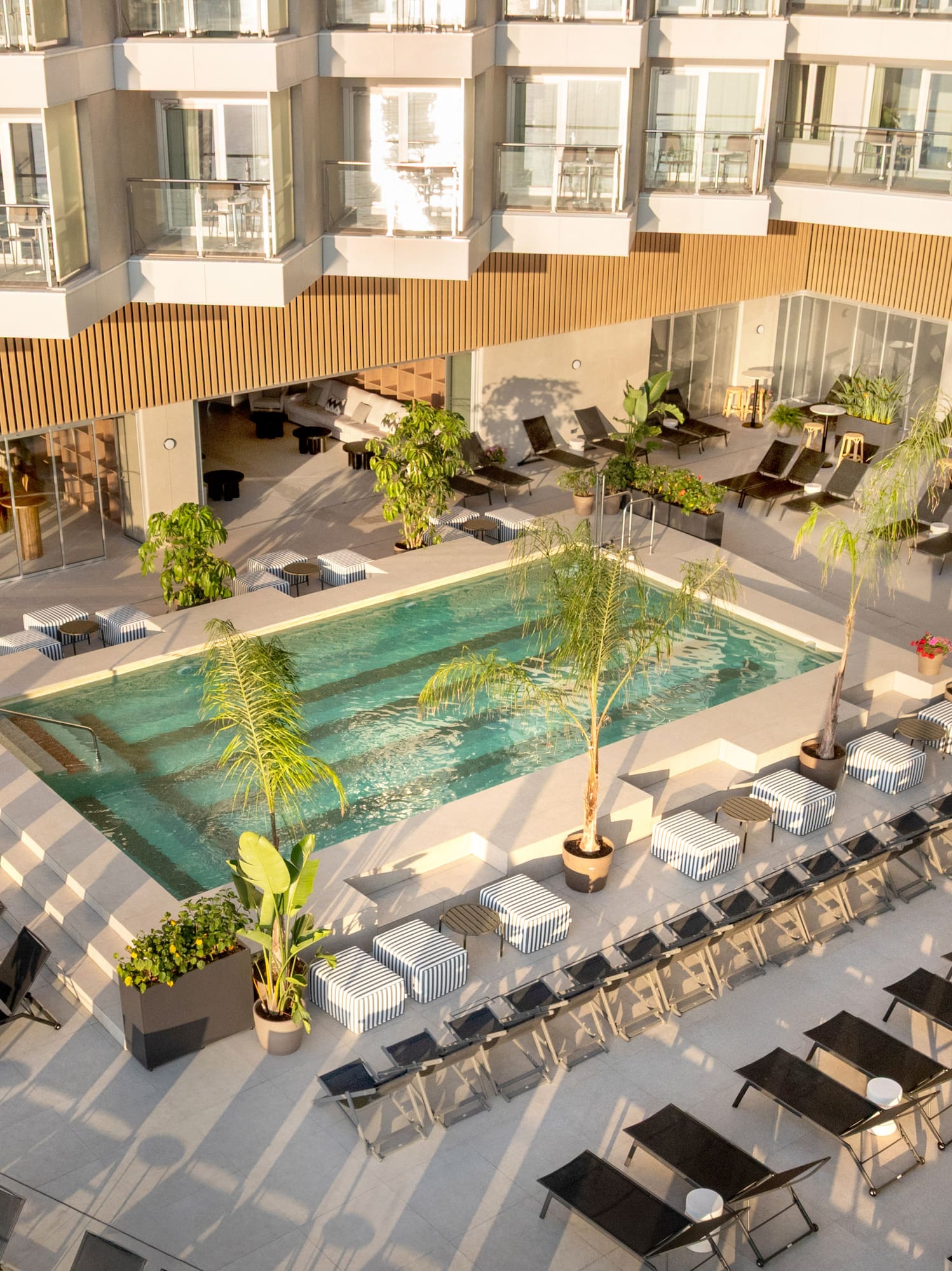 a pool with chairs and lounge chairs in a hotel