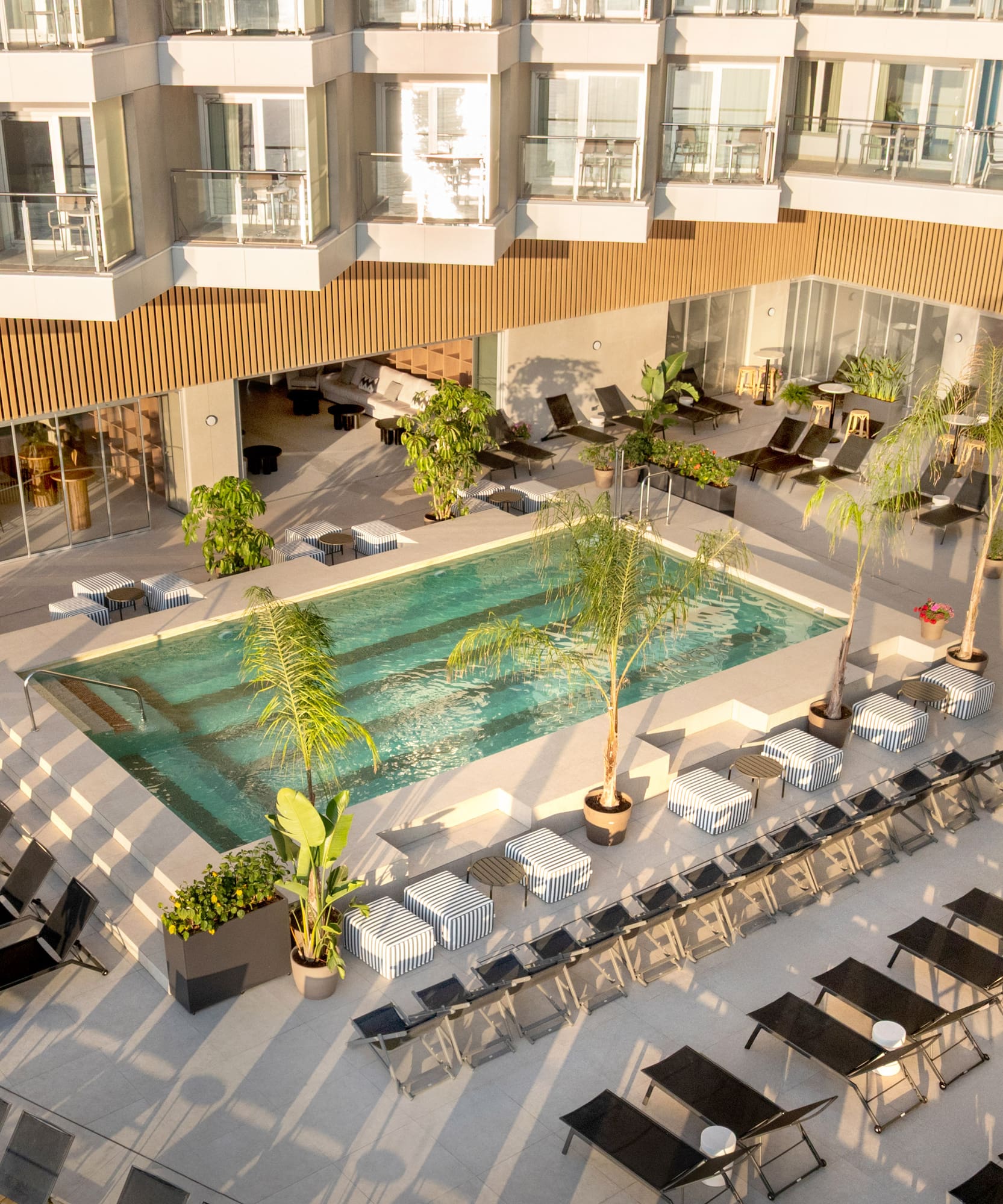 a pool with chairs and lounge chairs in a hotel