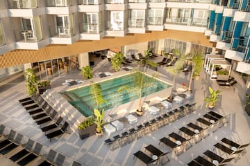 a pool with chairs and lounge chairs in a hotel