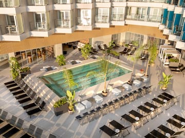 a pool with chairs and lounge chairs in a hotel