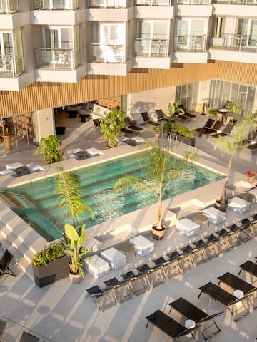 a pool with chairs and lounge chairs in a hotel