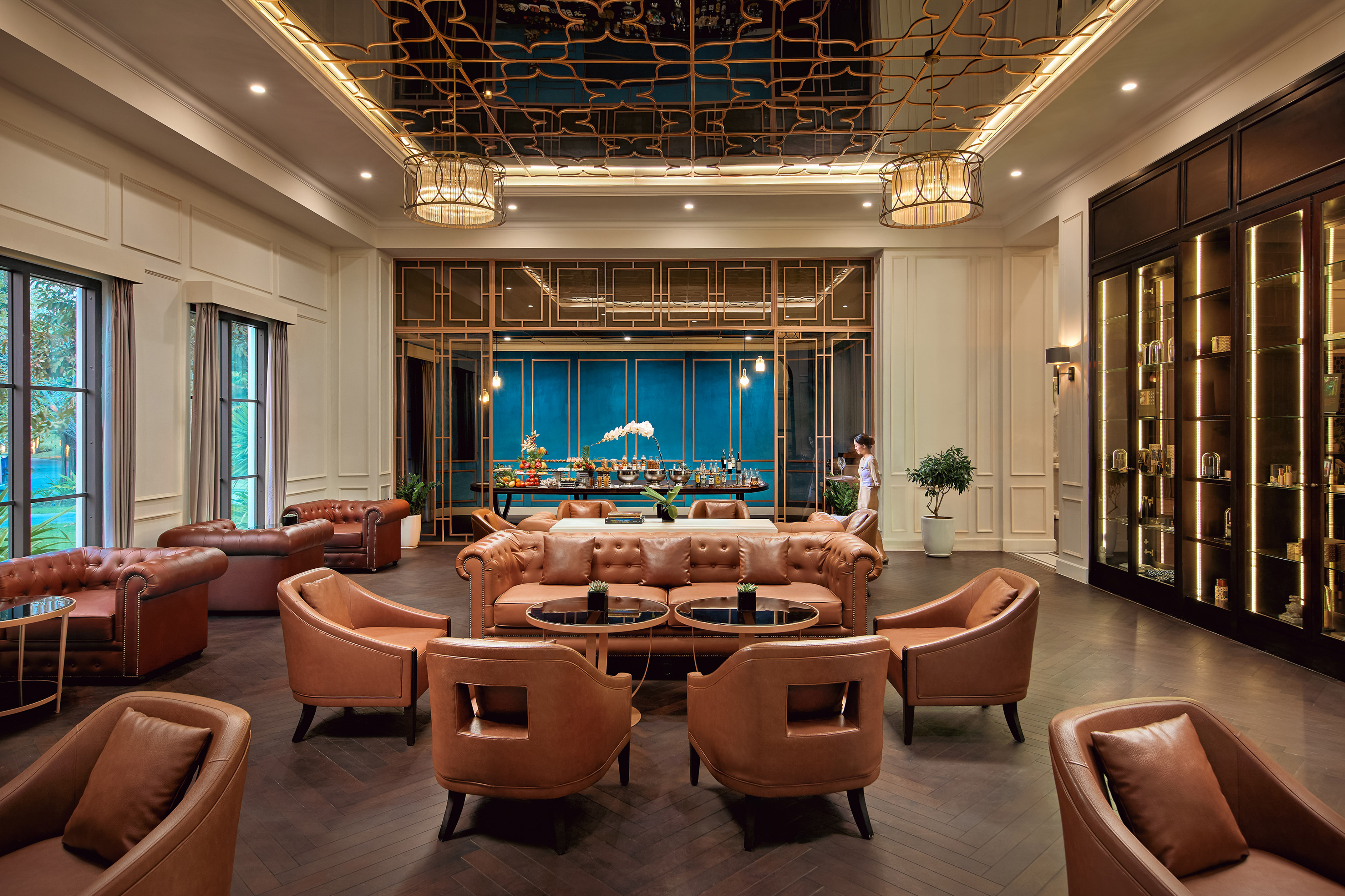 Luxury hotel lounge with brown leather seating, ornate ceiling, and refreshments.