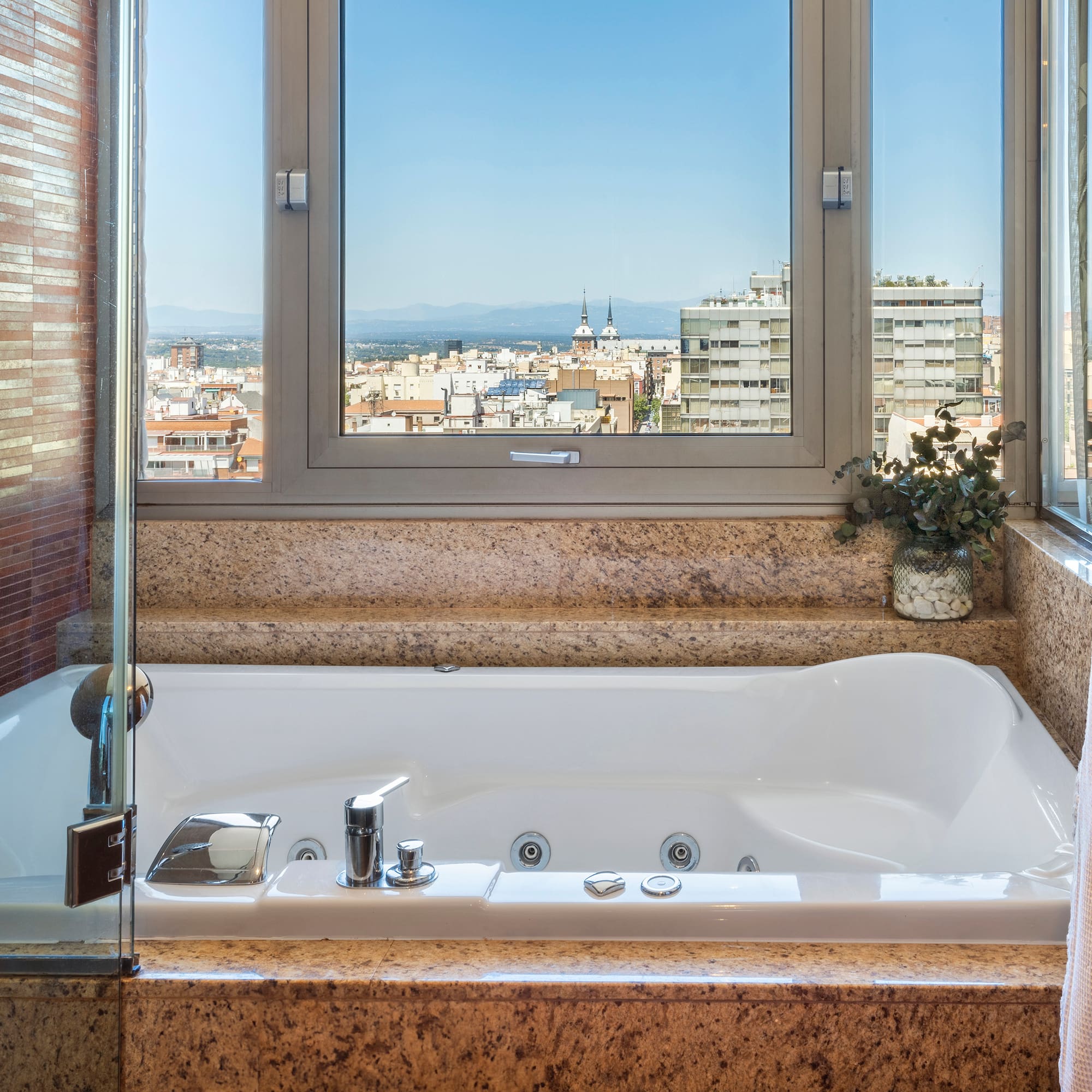 a bathtub with a window and a view of a city