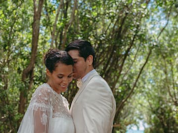 a man and woman standing in front of trees