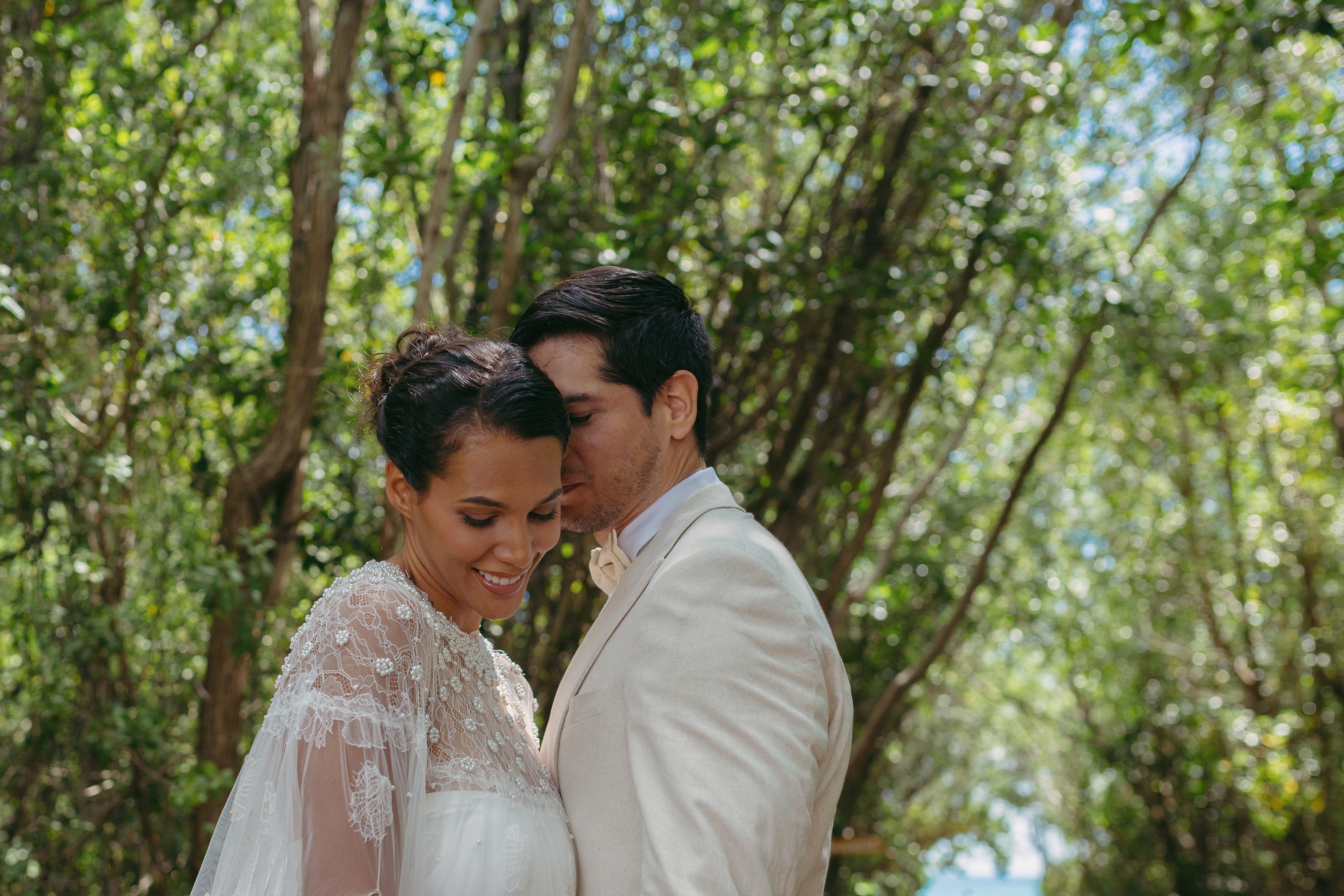 Bride and groom embracing outdoors in a romantic natural setting.