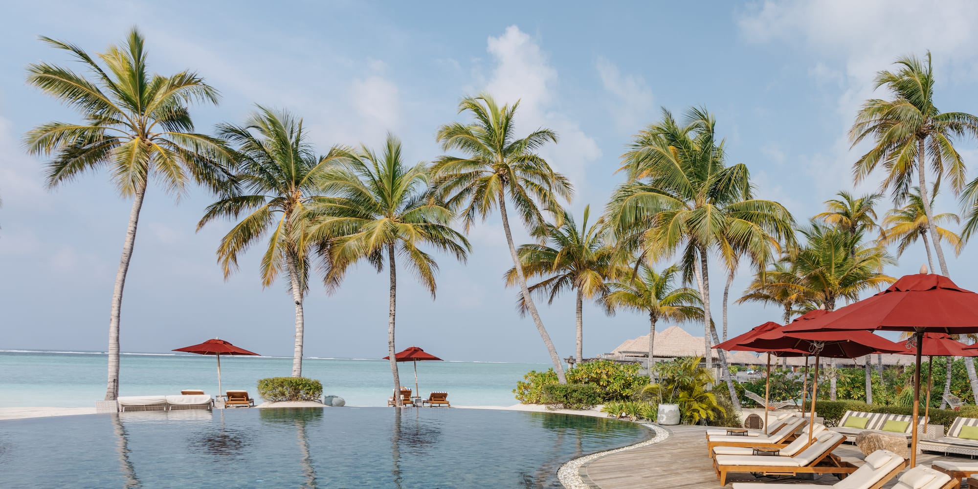 a pool with chairs and umbrellas by the water