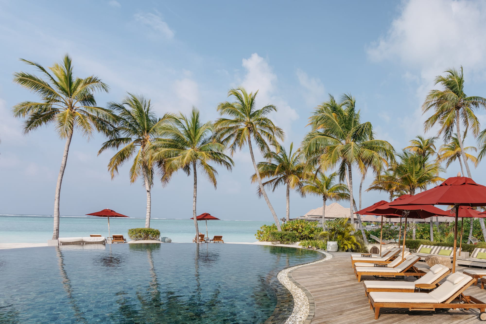 a pool with chairs and umbrellas by the water