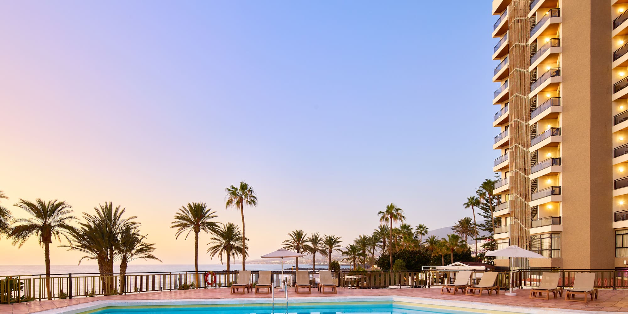 a pool with palm trees and a building