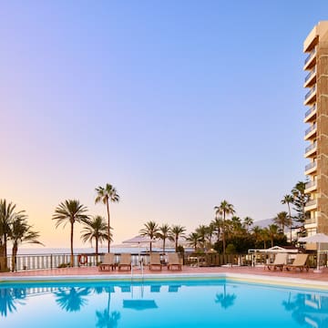 a pool with palm trees and a building