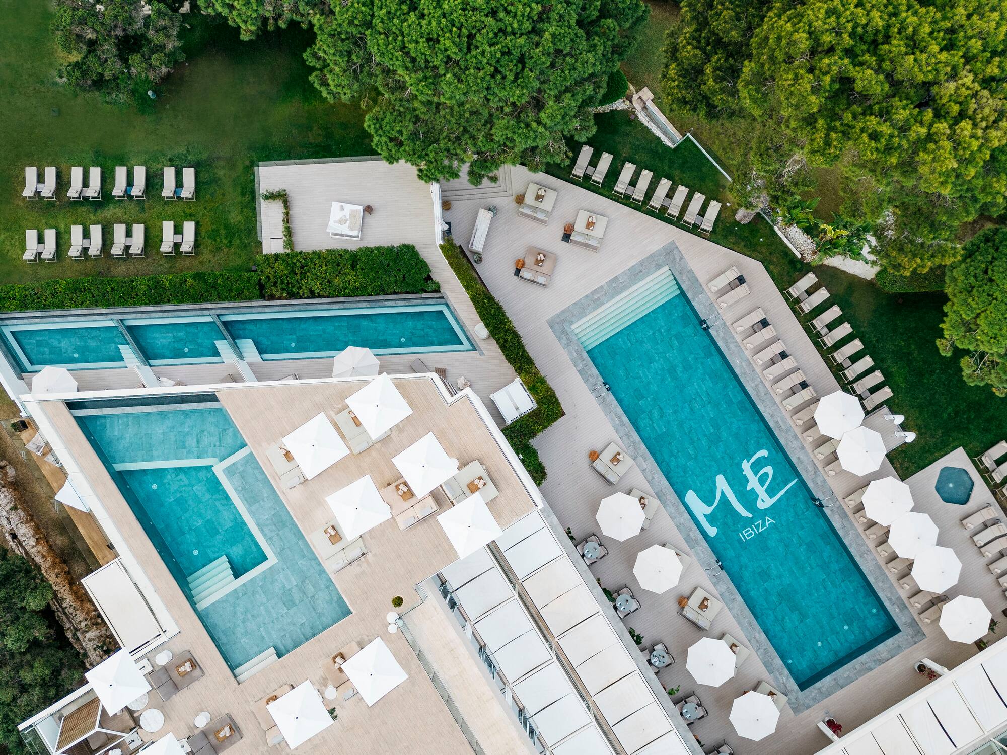 a swimming pool and chairs with umbrellas and lawns
