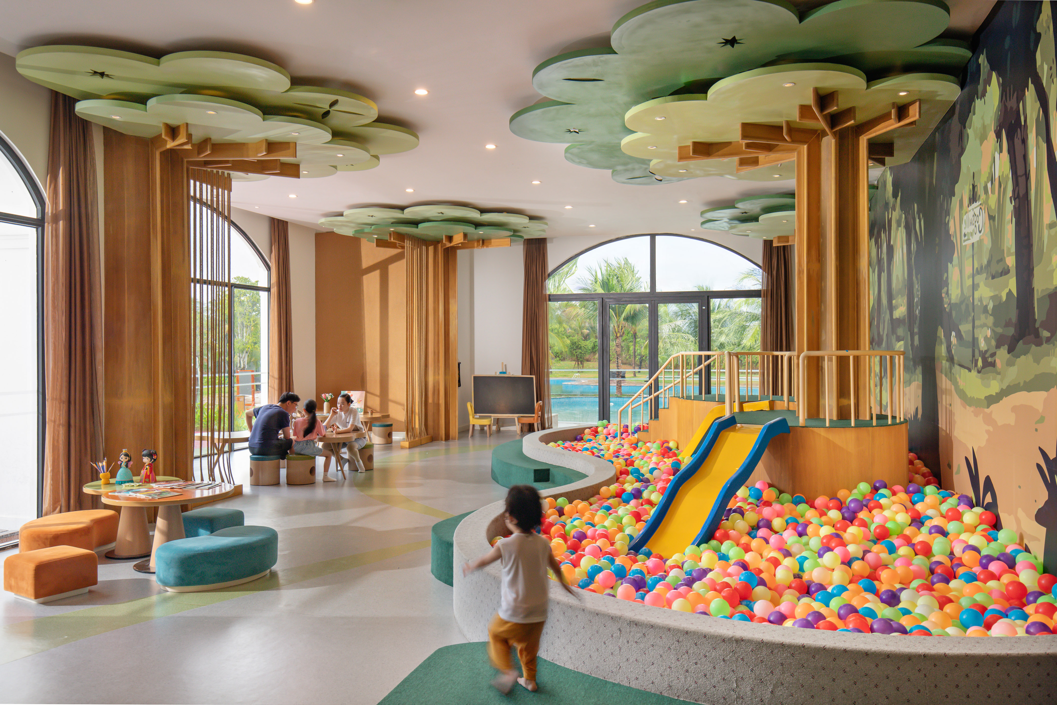 Vibrant kids' play area featuring a colorful ball pit, slide, and tree decor.