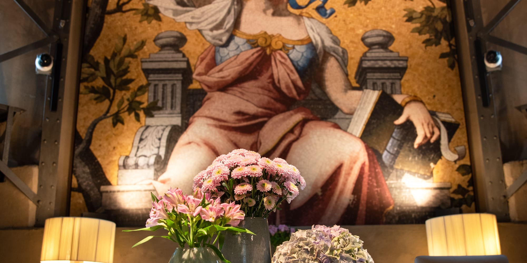 a table with vases of flowers and a painting on the wall