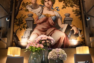 a table with vases of flowers and a painting on the wall