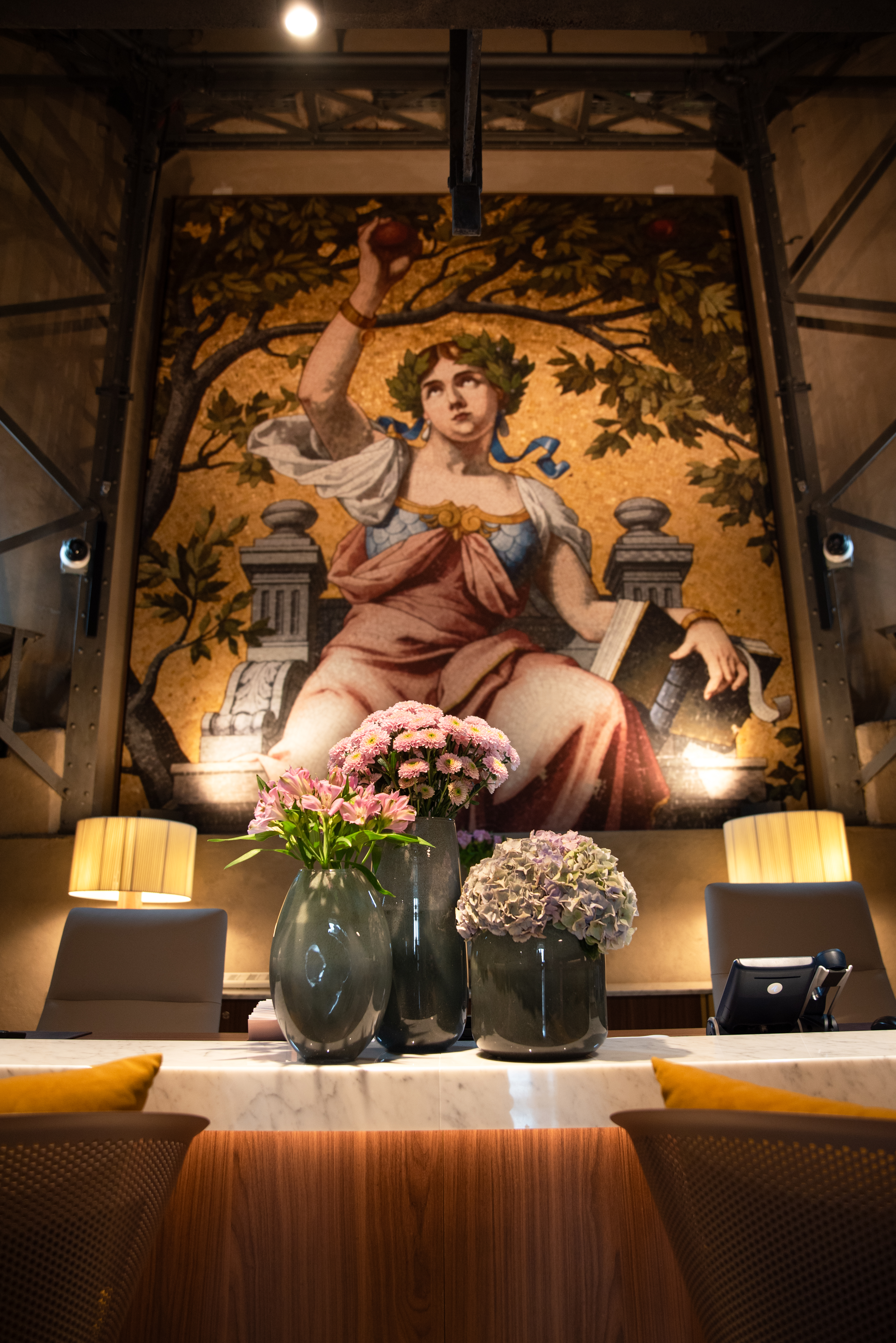 Hotel lobby reception with flowers and large classical mosaic mural.