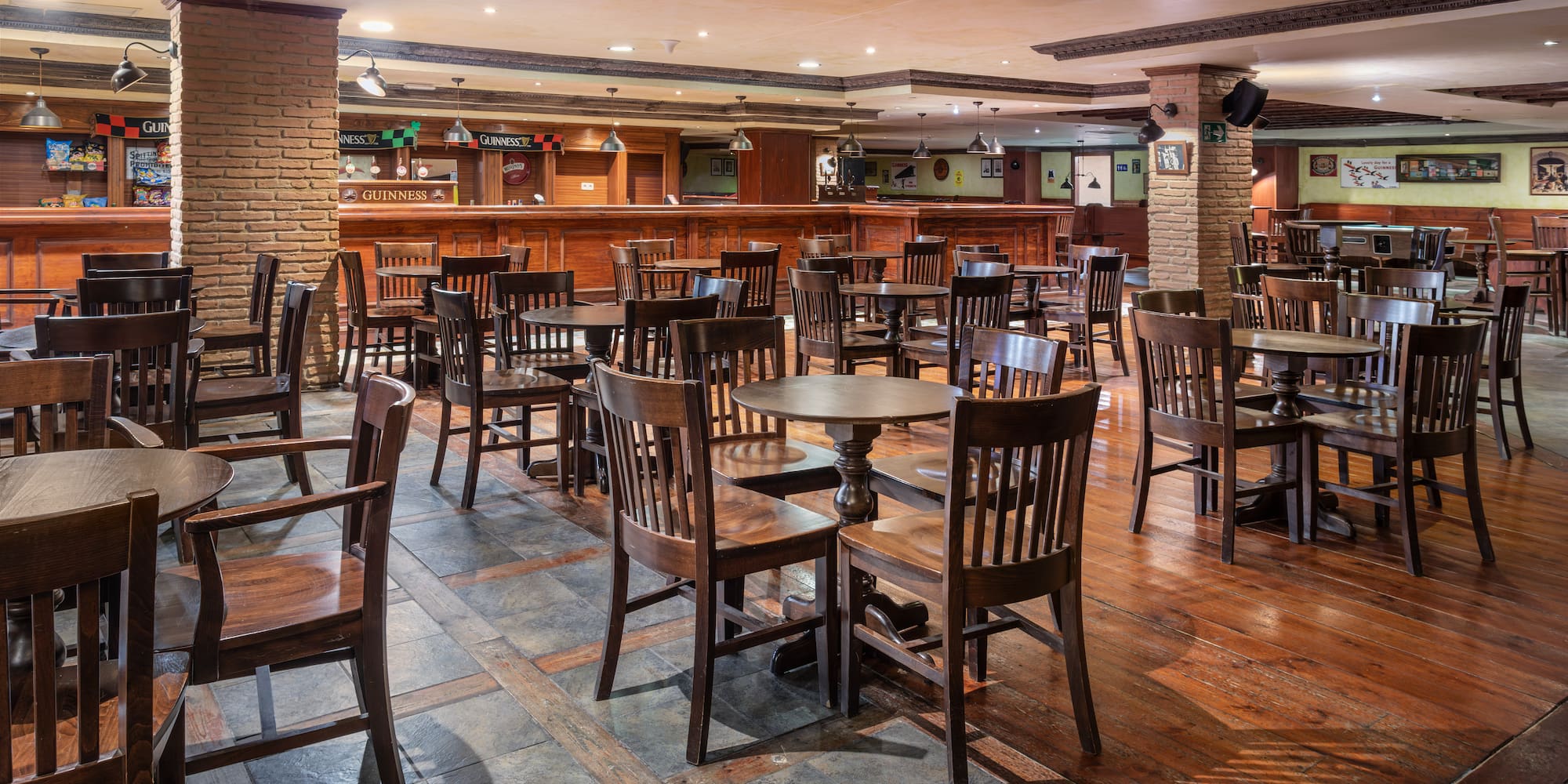 Irish pub interior with wooden tables, chairs, and a long bar counter.