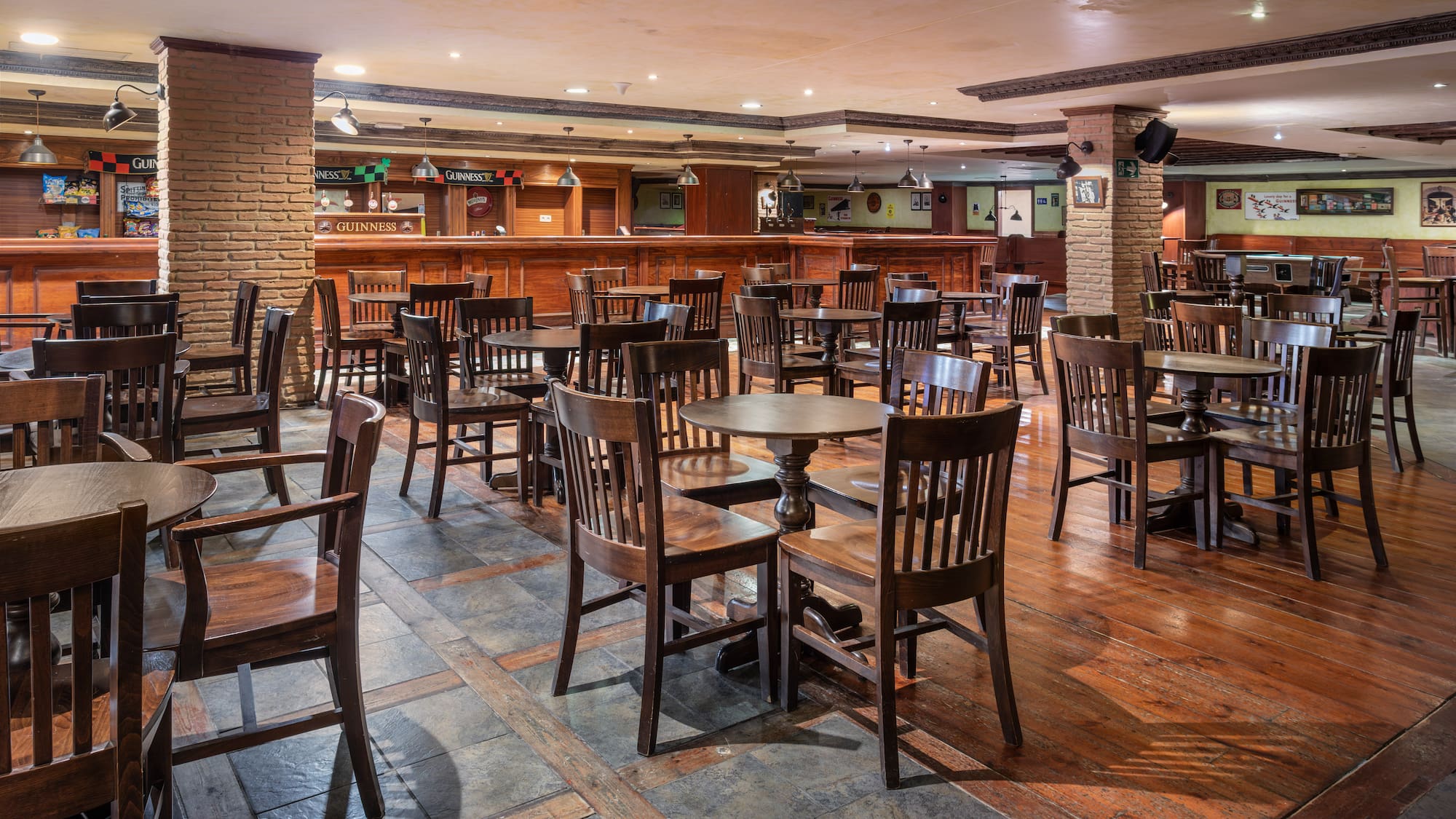 Irish pub interior with wooden tables, chairs, and a long bar counter.