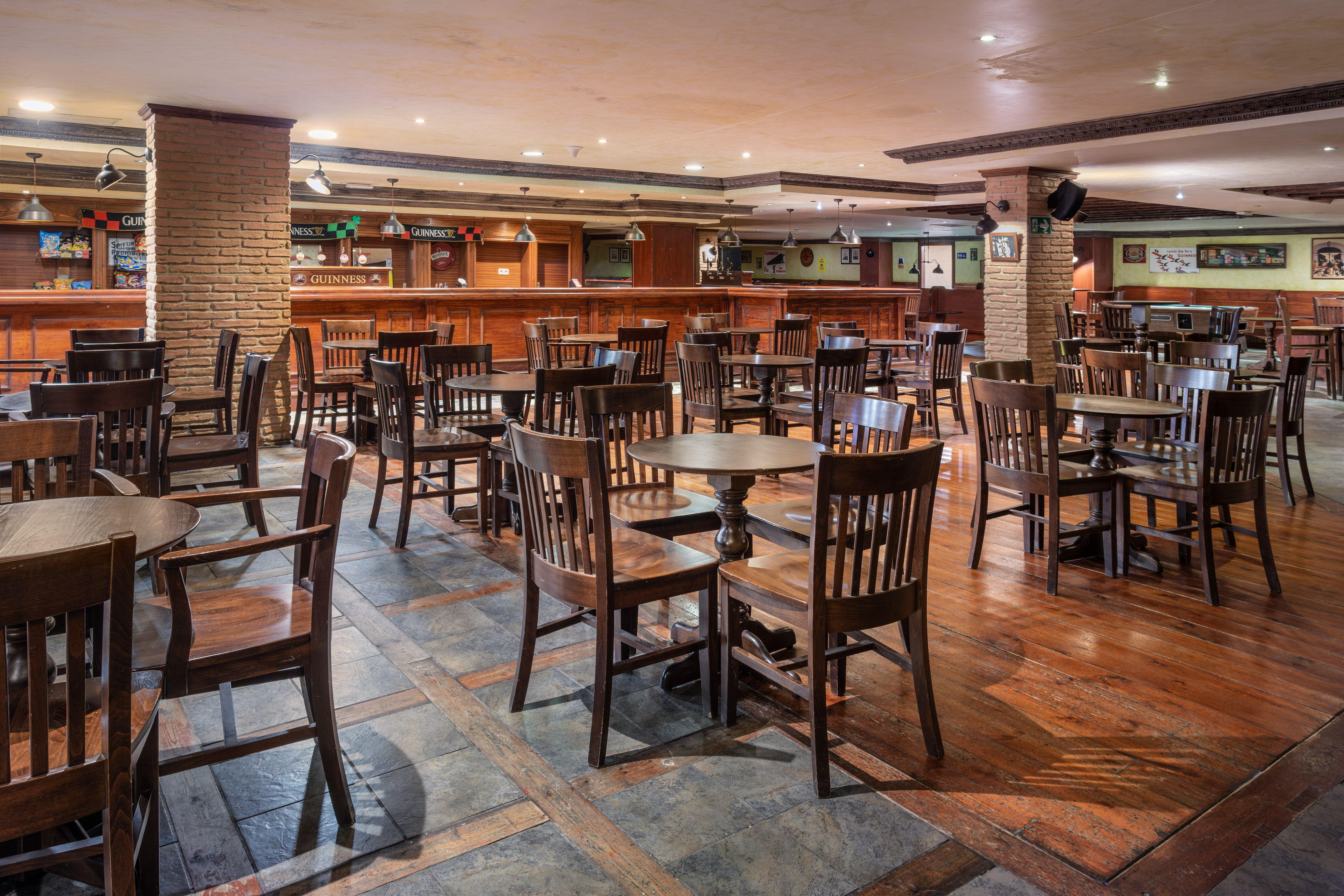 Irish pub interior with wooden tables, chairs, and a long bar counter.