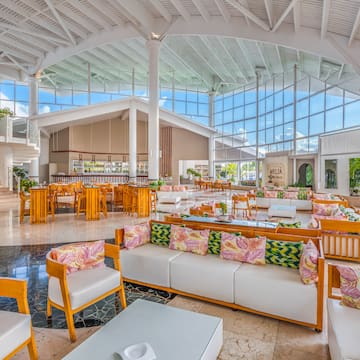 a large room with white furniture and wooden tables