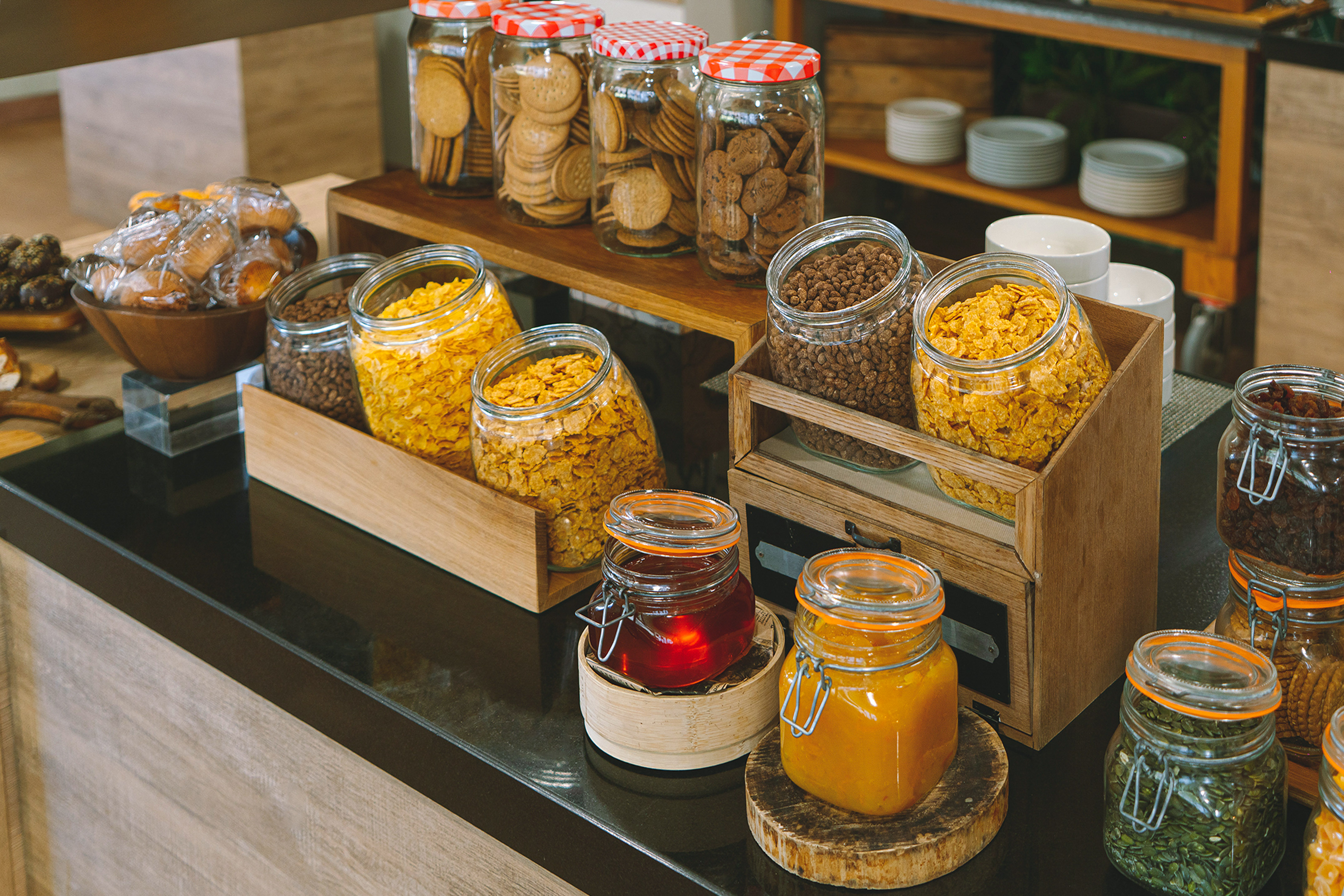 Breakfast buffet with jars of cereals, cookies, jams, and dried fruits.
