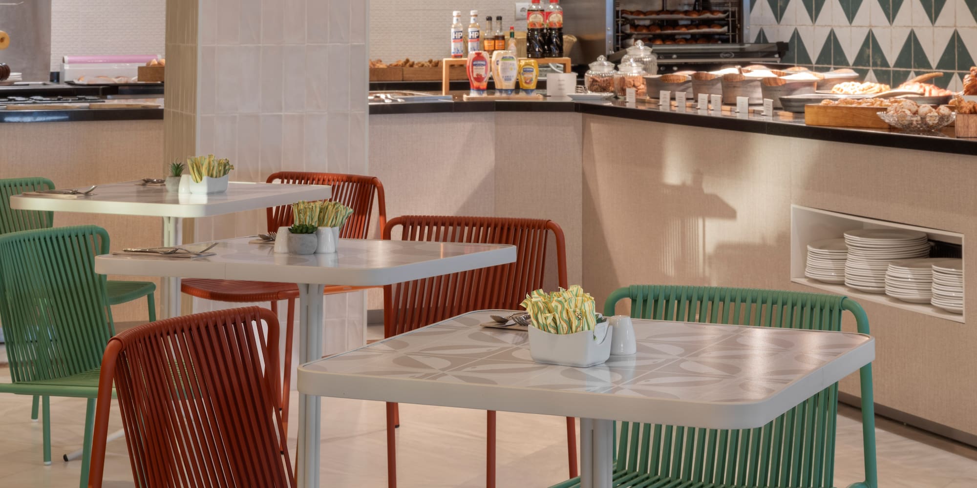 Modern cafe interior with breakfast buffet and colorful dining chairs.