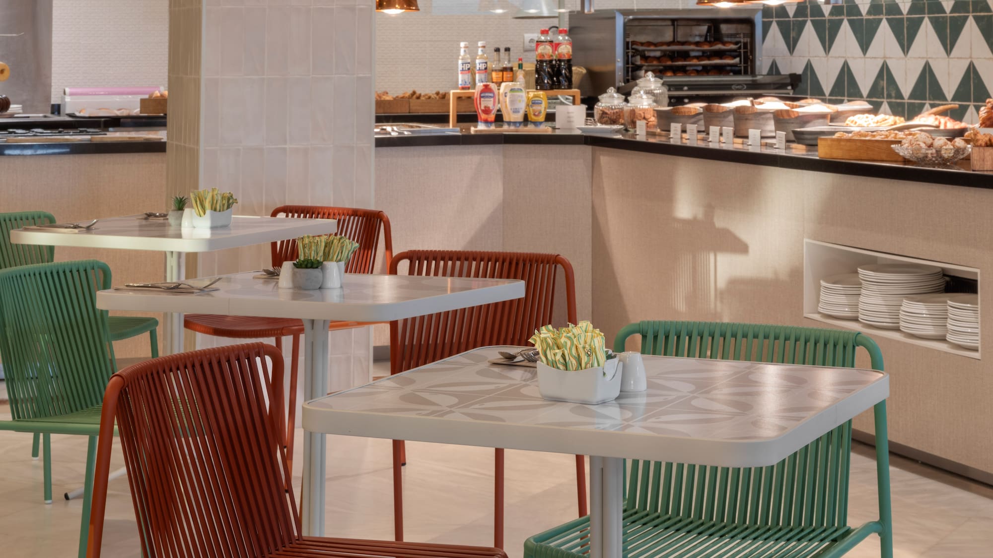 Modern cafe interior with breakfast buffet and colorful dining chairs.