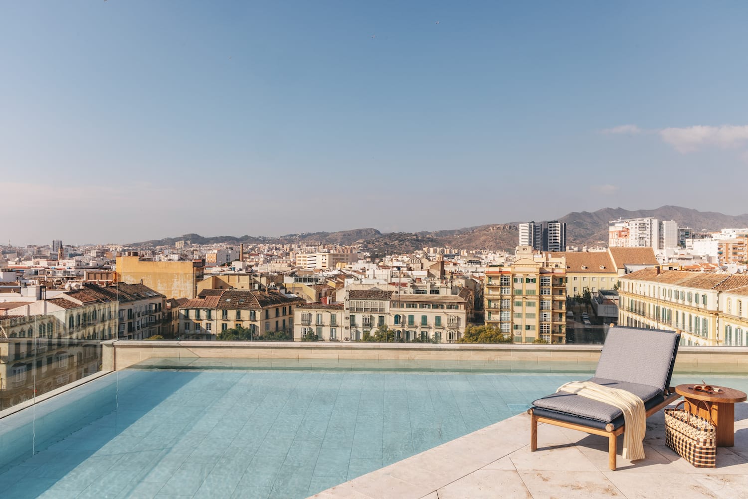 a pool with a lounge chair and a city in the background