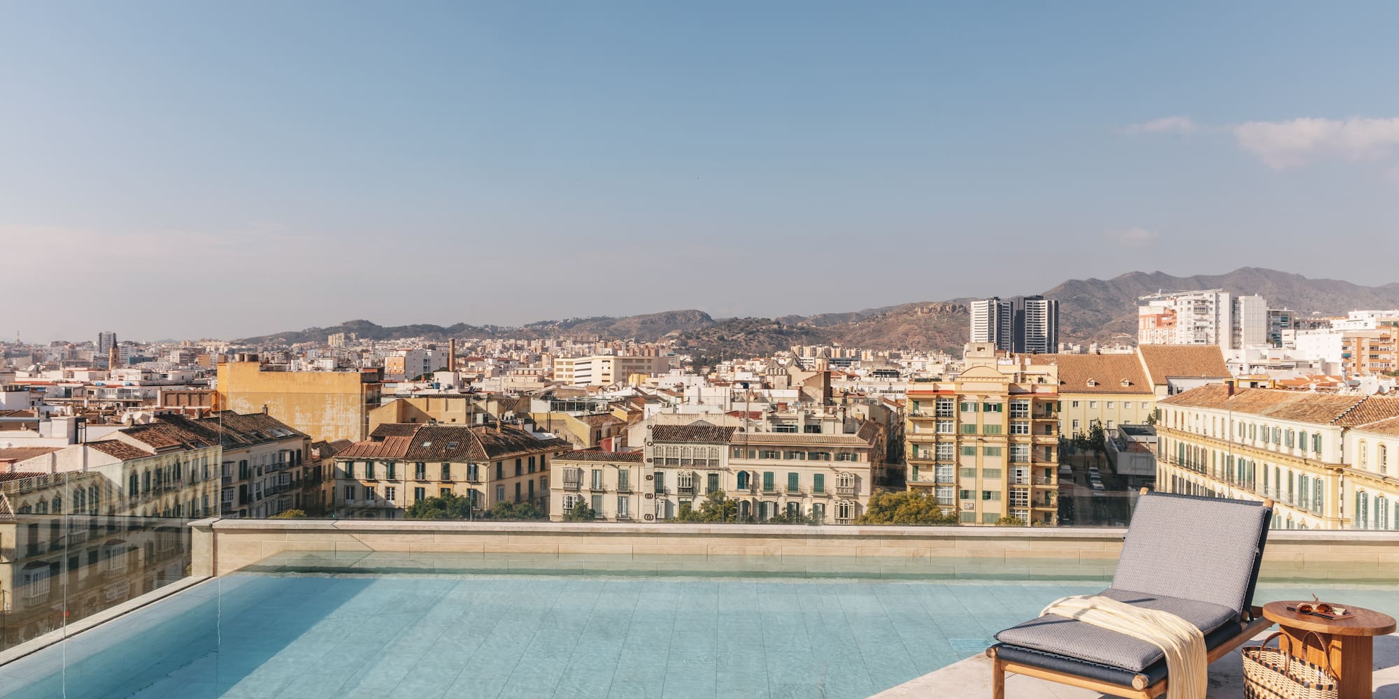 a pool with a lounge chair and a city in the background