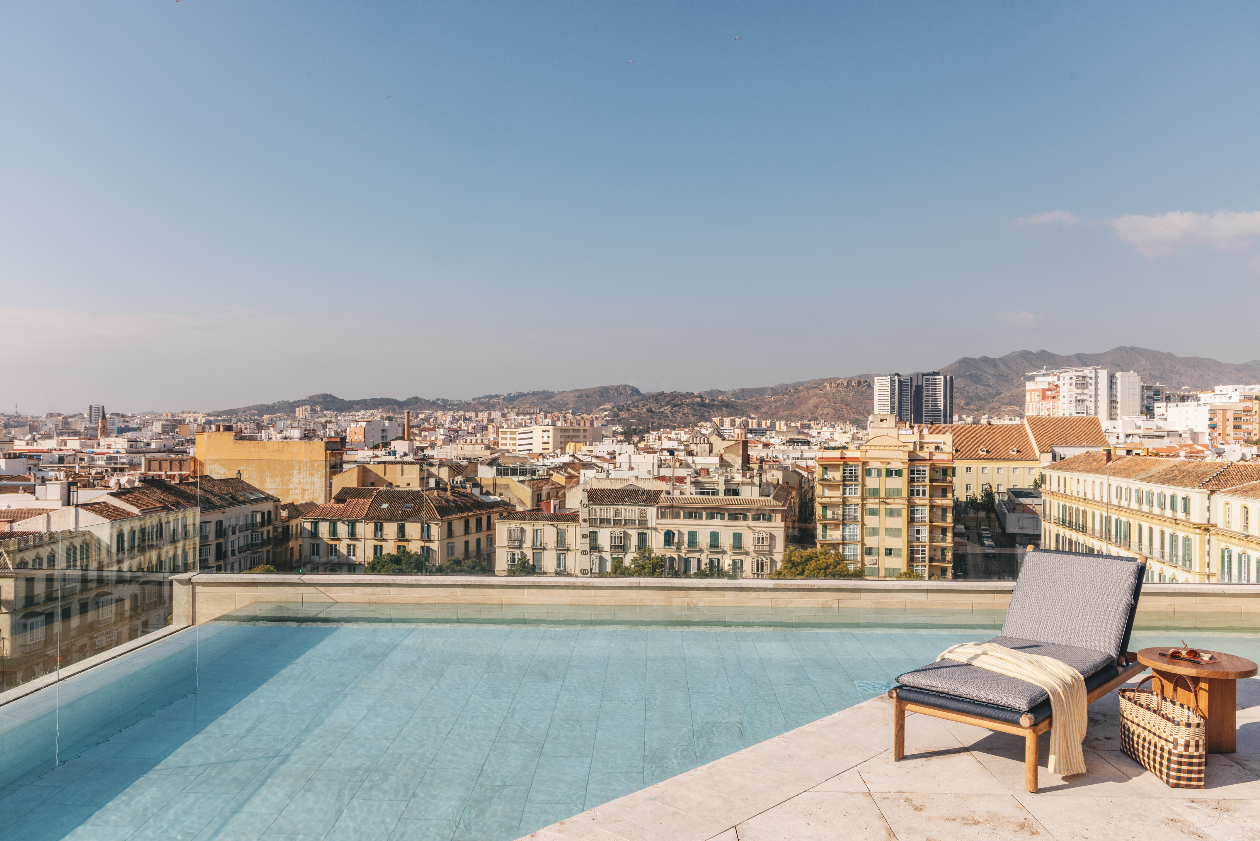a pool with a lounge chair and a city in the background