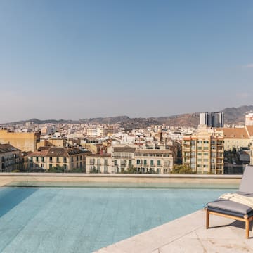 a pool with a lounge chair and a city in the background
