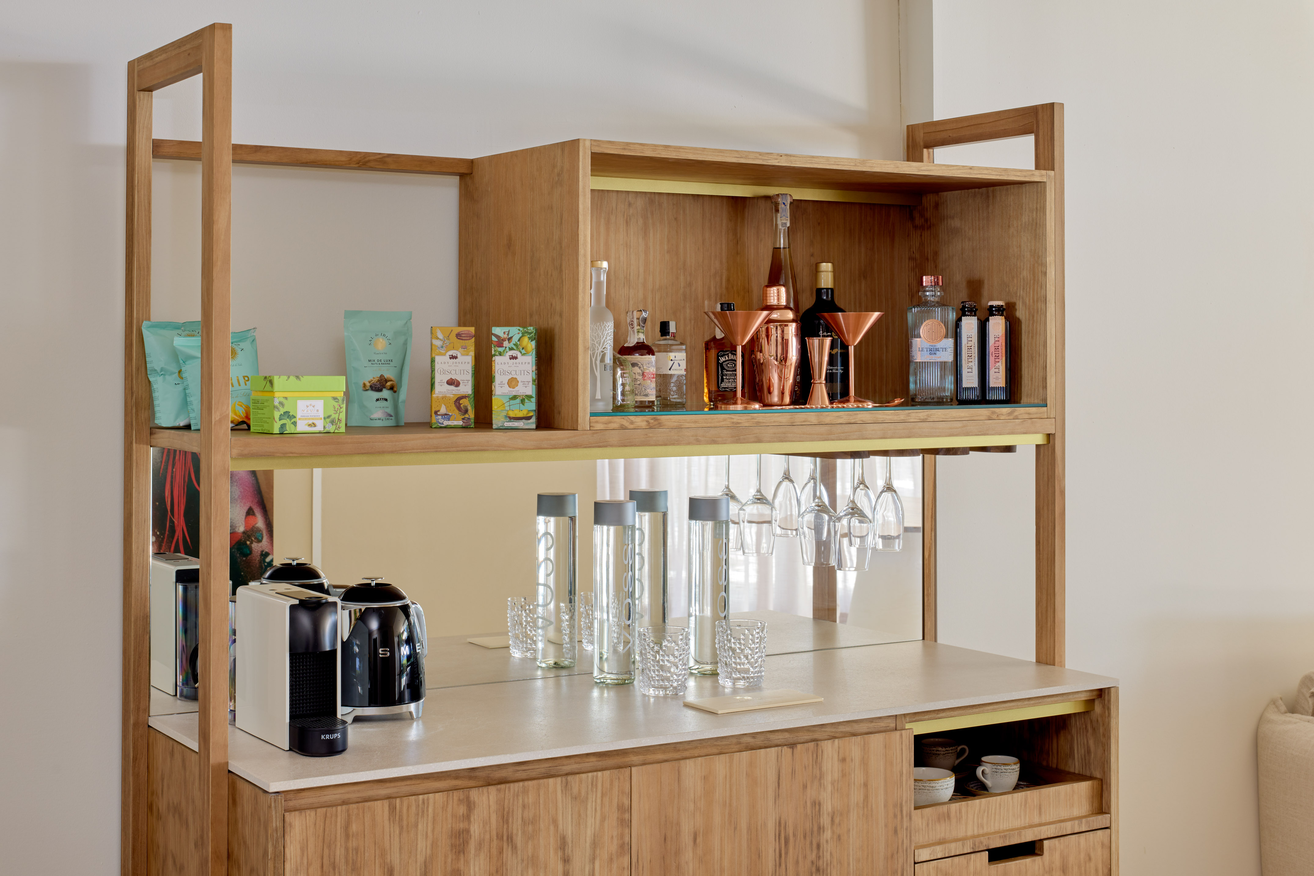 Stylish wooden minibar featuring coffee machine, liquor, snacks, and barware.