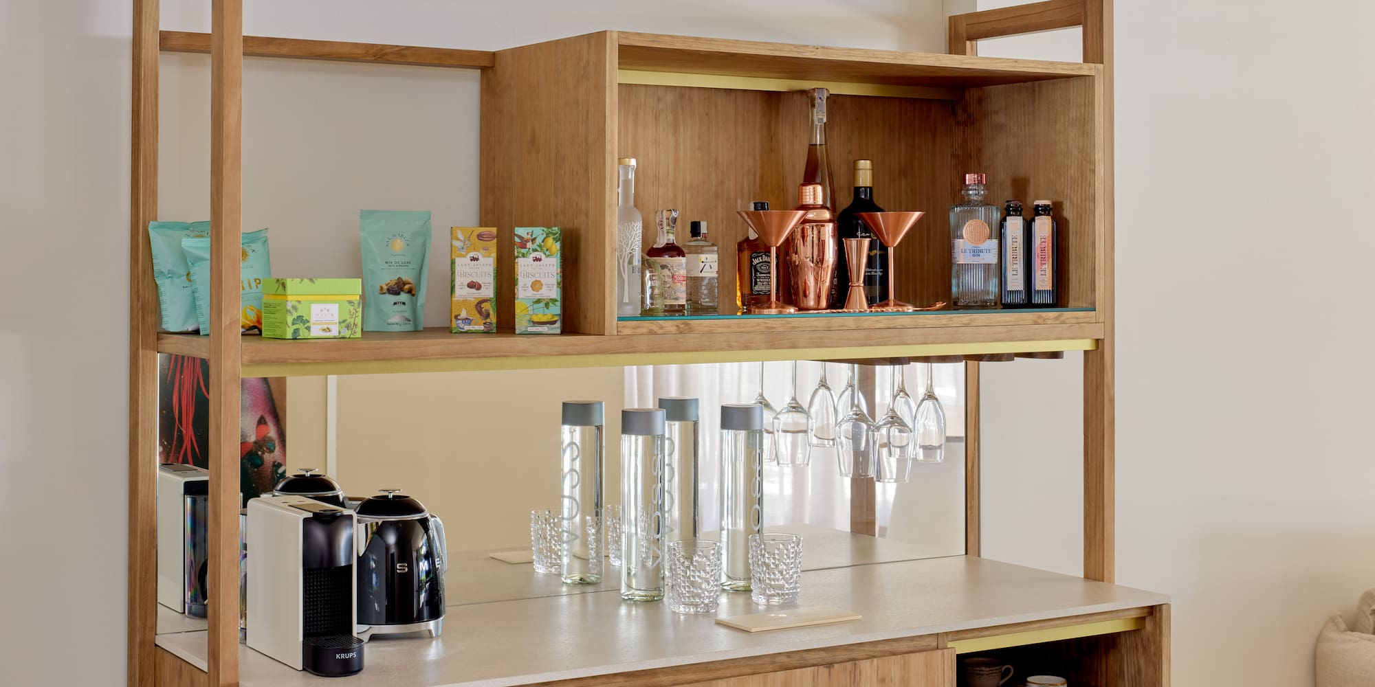 Stylish wooden minibar featuring coffee machine, liquor, snacks, and barware.