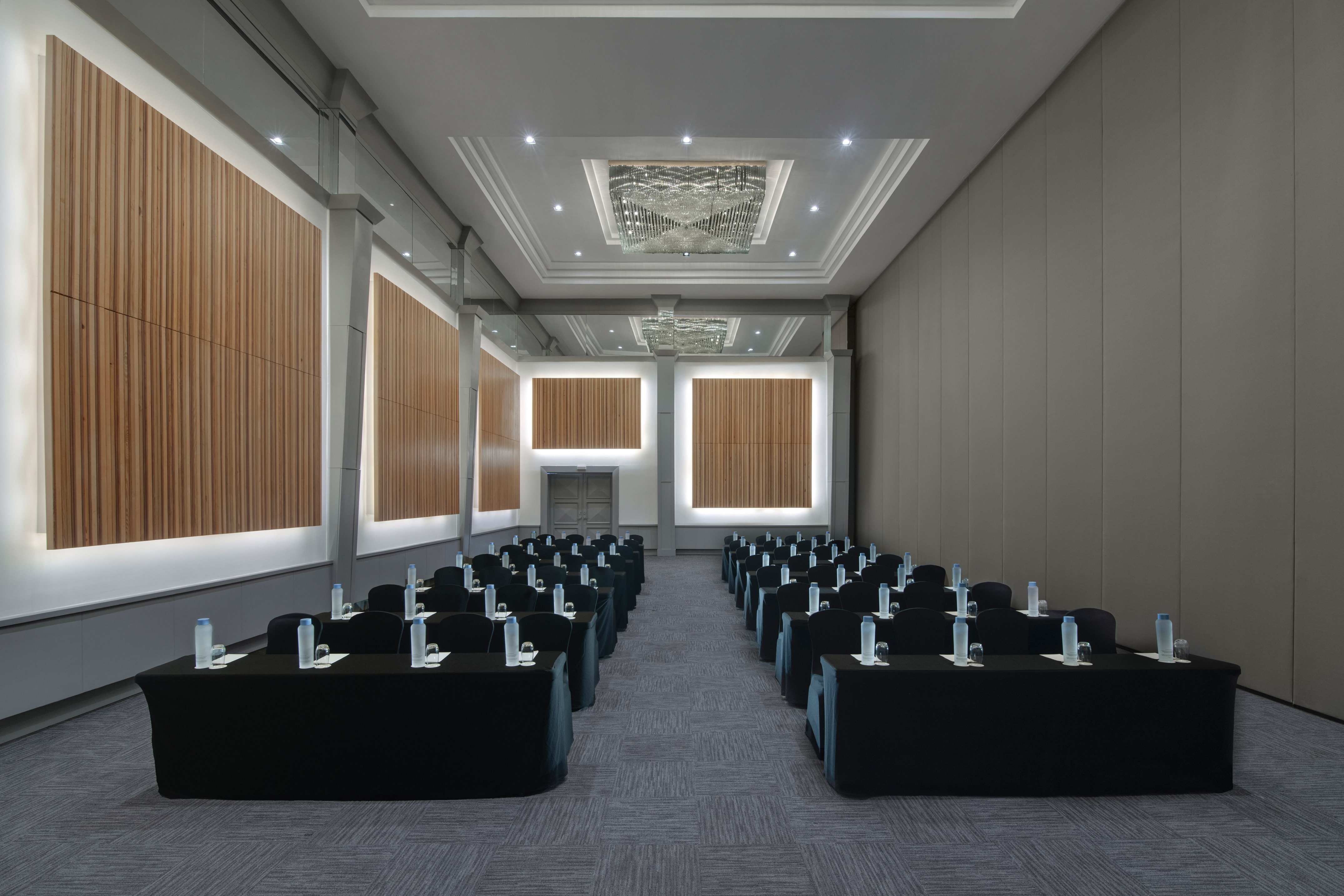 Modern conference room with rows of tables, chairs, and elegant wood walls.