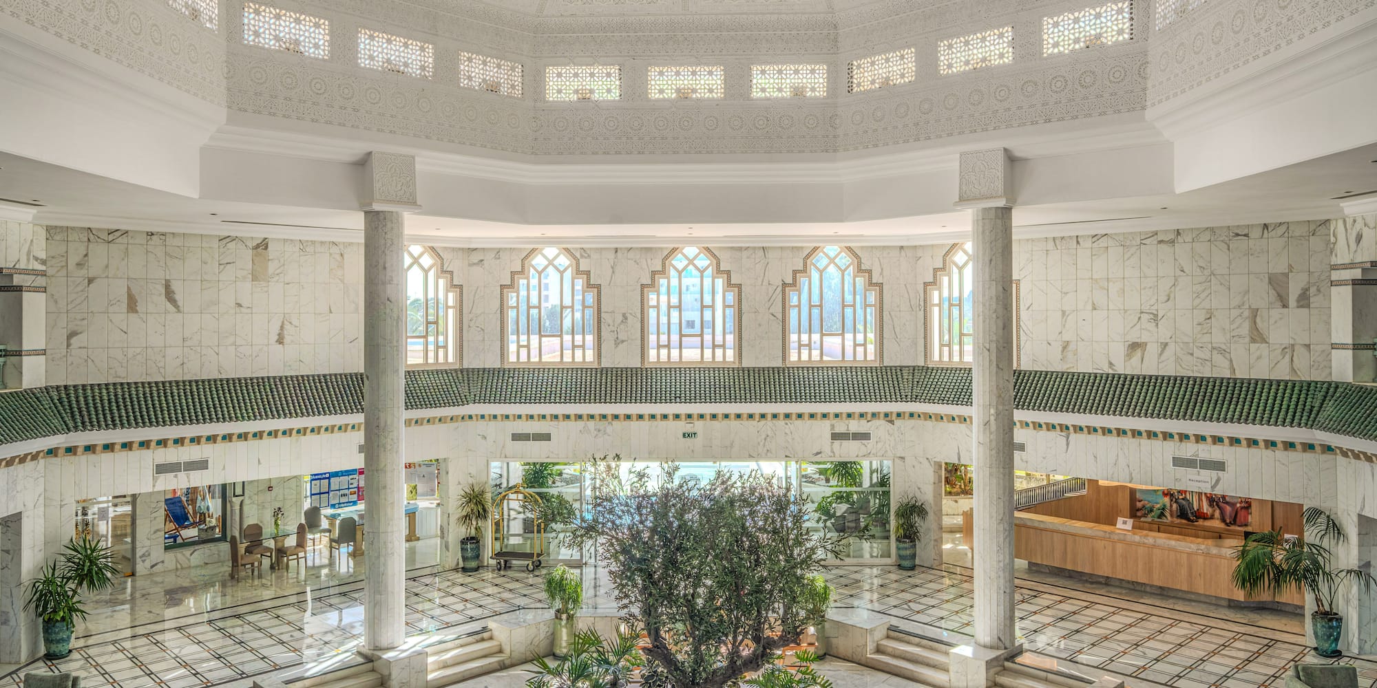 Luxury hotel lobby atrium, ornate Moroccan design, central tree, marble.