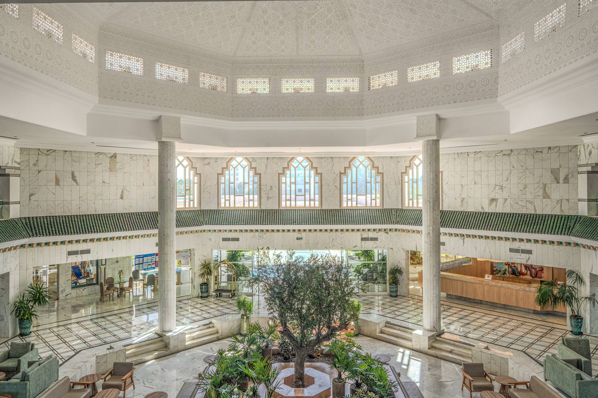 Luxury hotel lobby atrium, ornate Moroccan design, central tree, marble.