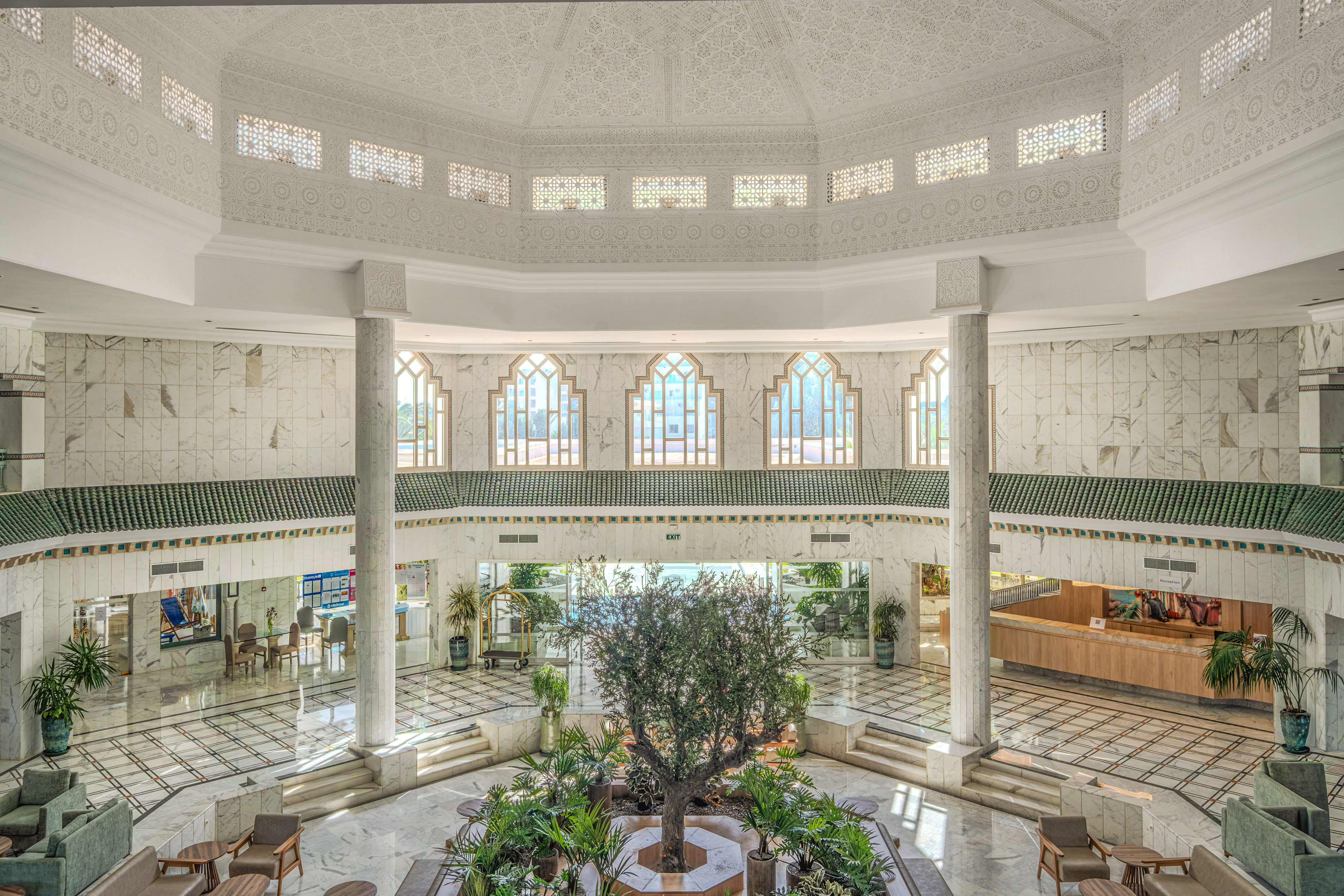 Luxury hotel lobby atrium, ornate Moroccan design, central tree, marble.