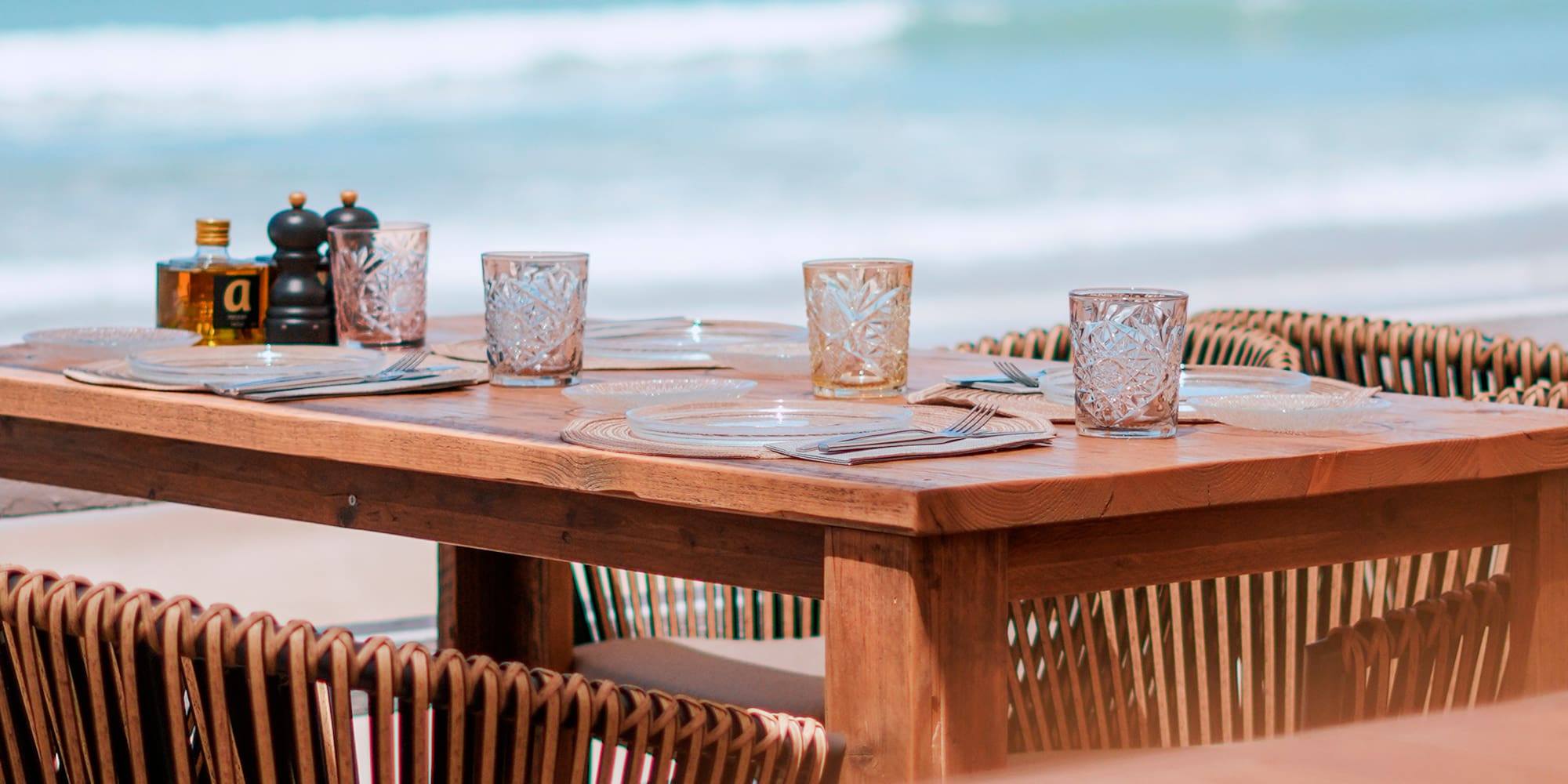 a table with glasses and plates on a beach