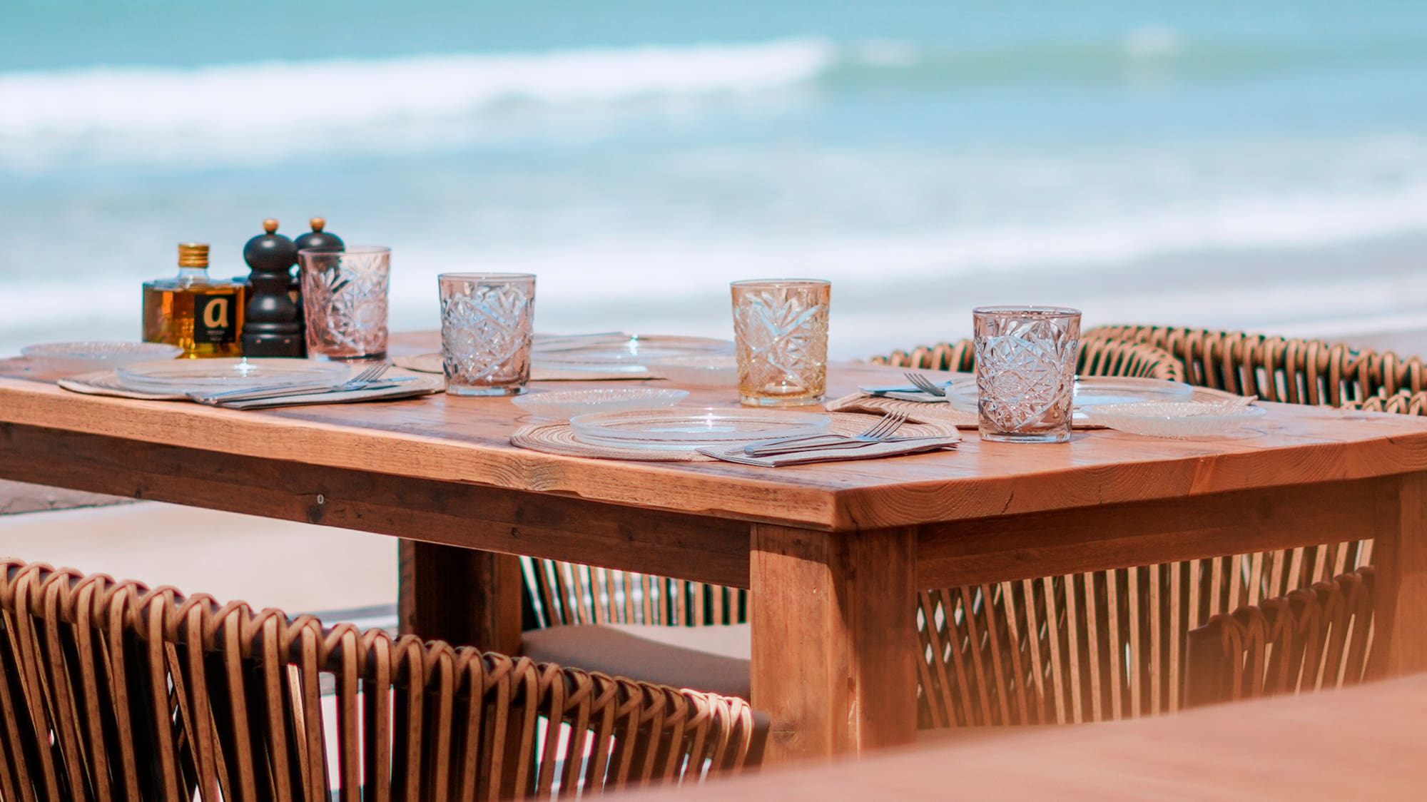 a table with glasses and plates on a beach