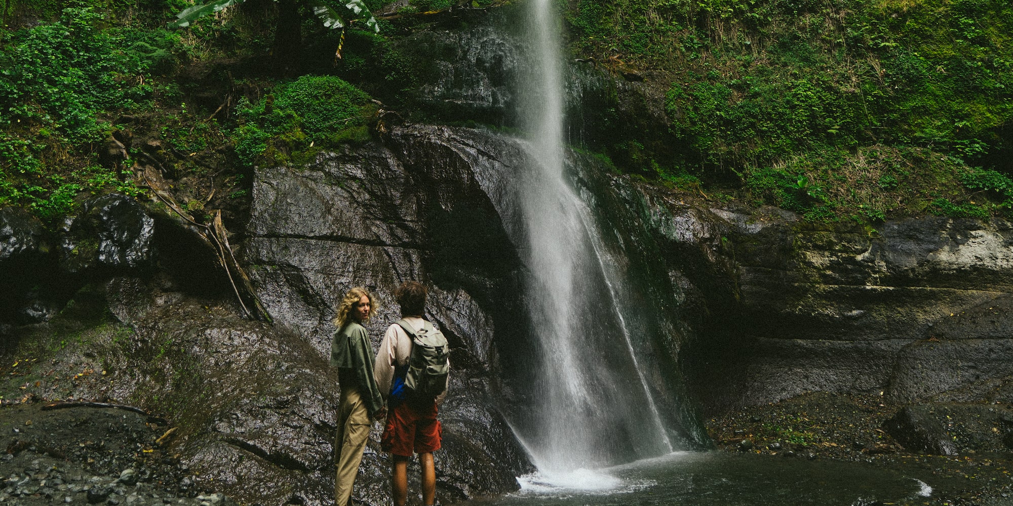 a couple of people standing next to a waterfall