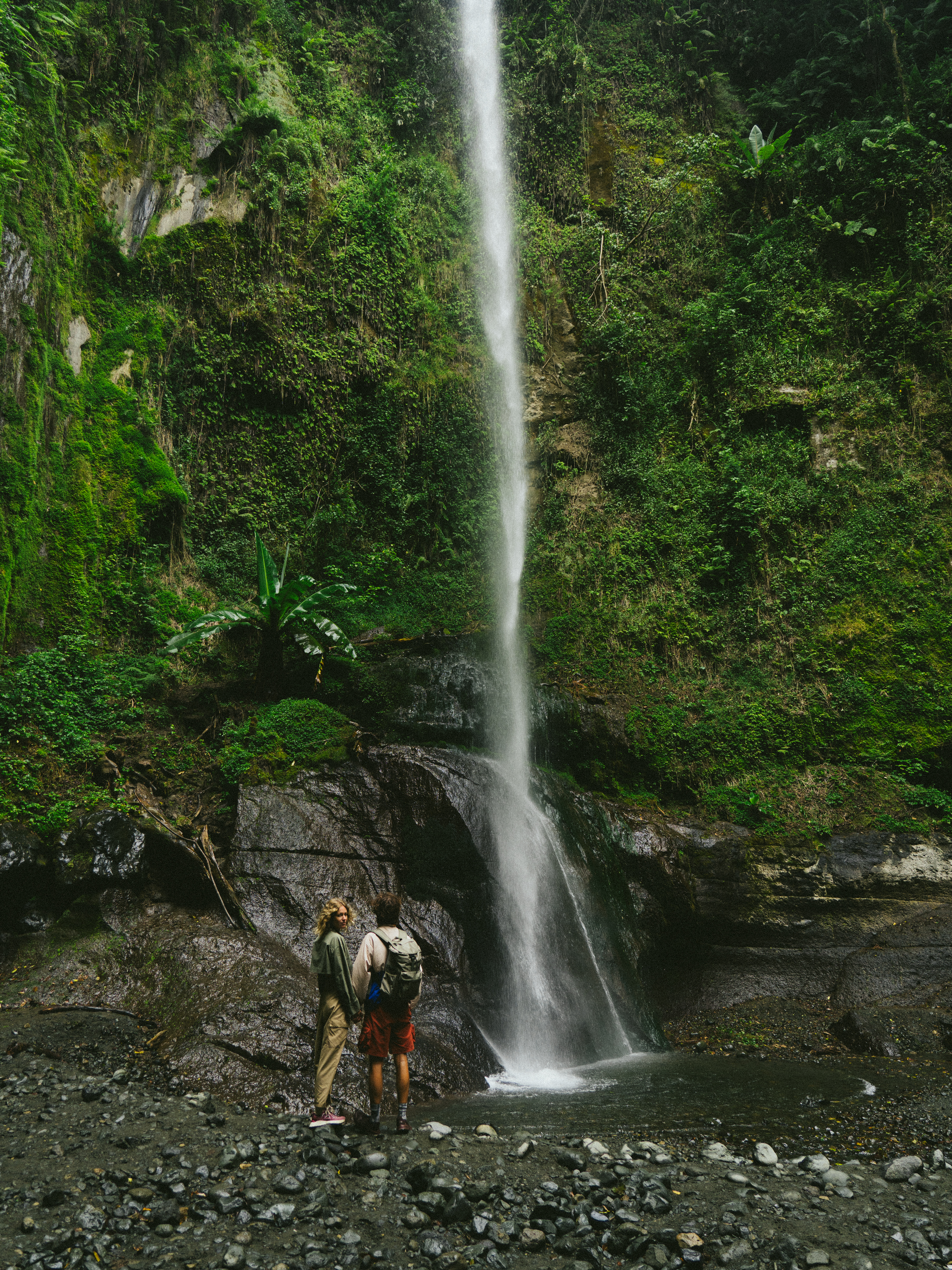 a couple of people standing next to a waterfall