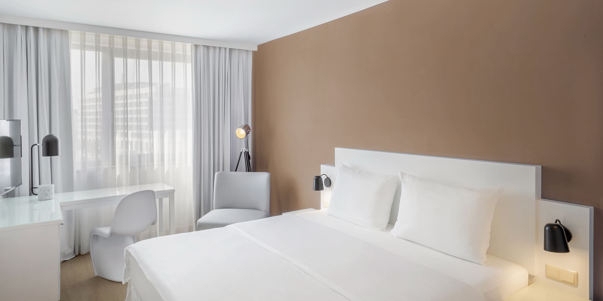 a bed with white sheets and a desk in a room