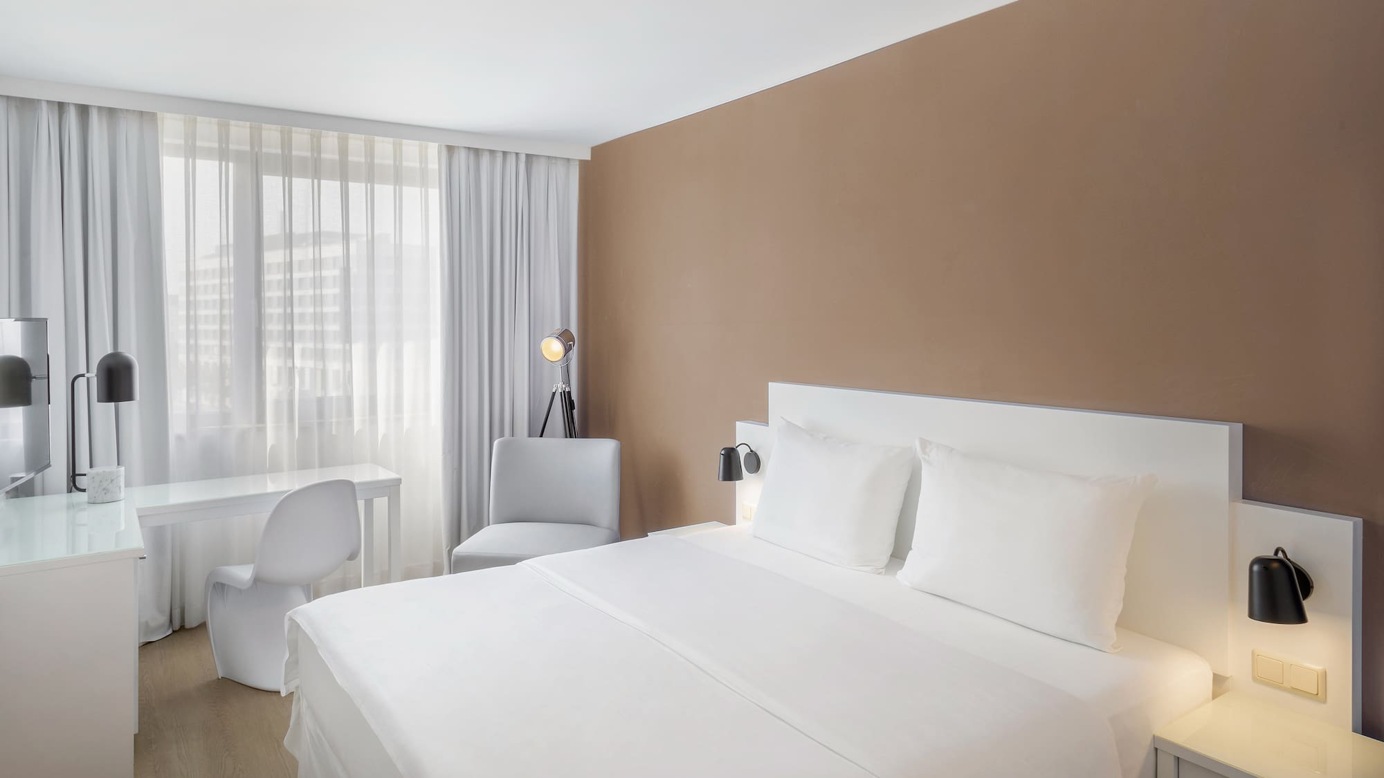 a bed with white sheets and a desk in a room