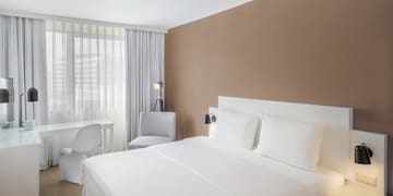 a bed with white sheets and a desk in a room