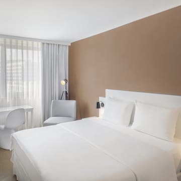 a bed with white sheets and a desk in a room