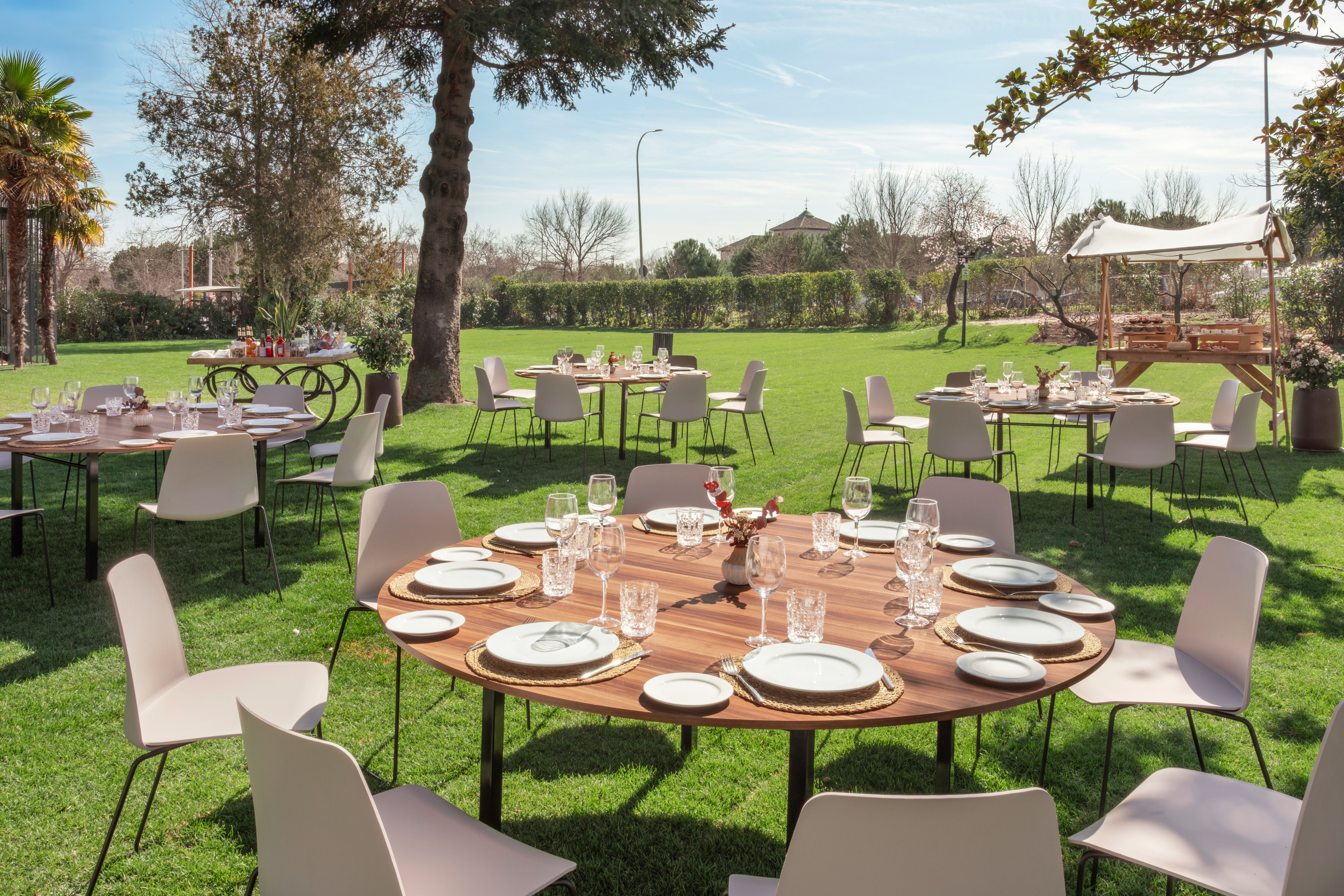 Alfresco dining tables set for an outdoor event on a lush green lawn.